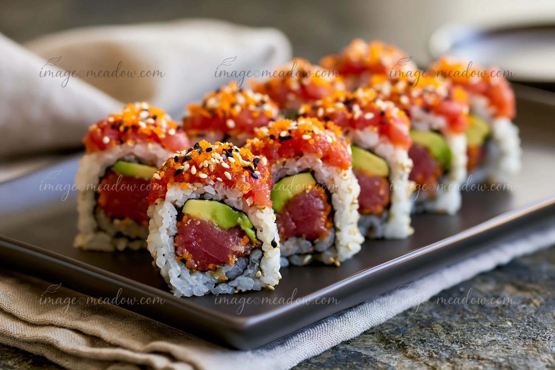 A close-up view showcases a spicy tuna roll neatly arranged on a black plate.