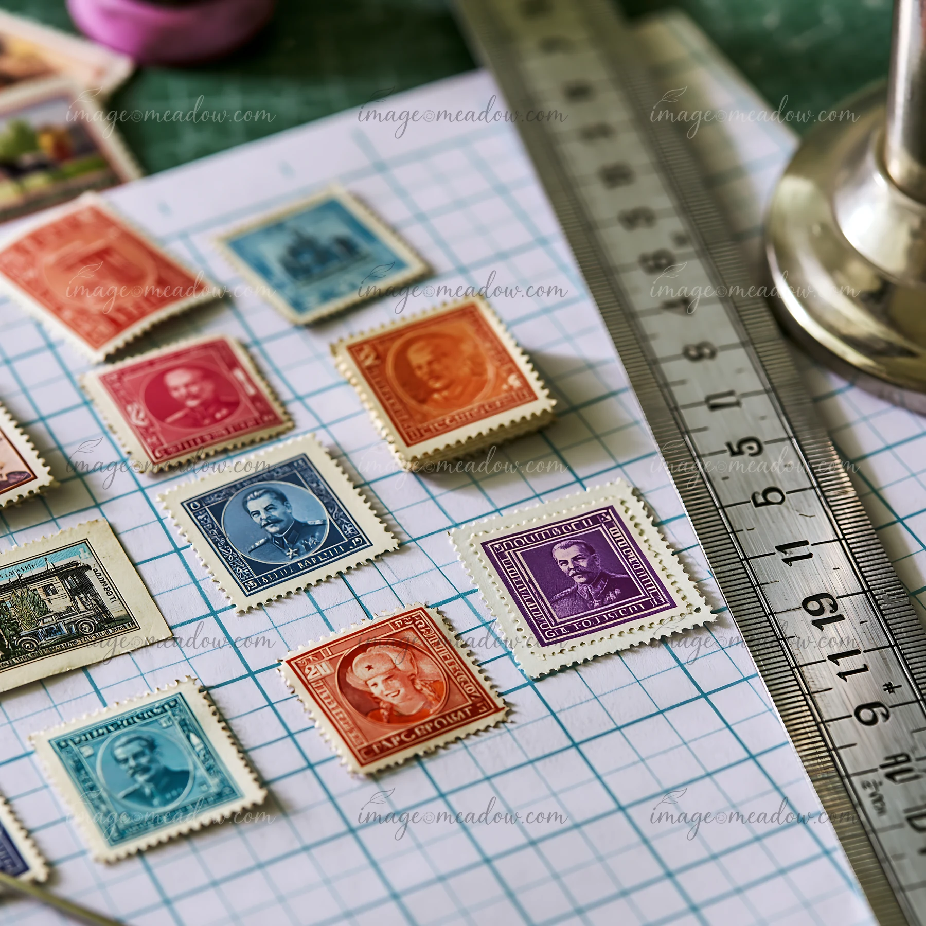 A collection of Soviet postage stamps is arranged on grid paper beside a ruler and a spool of thread.