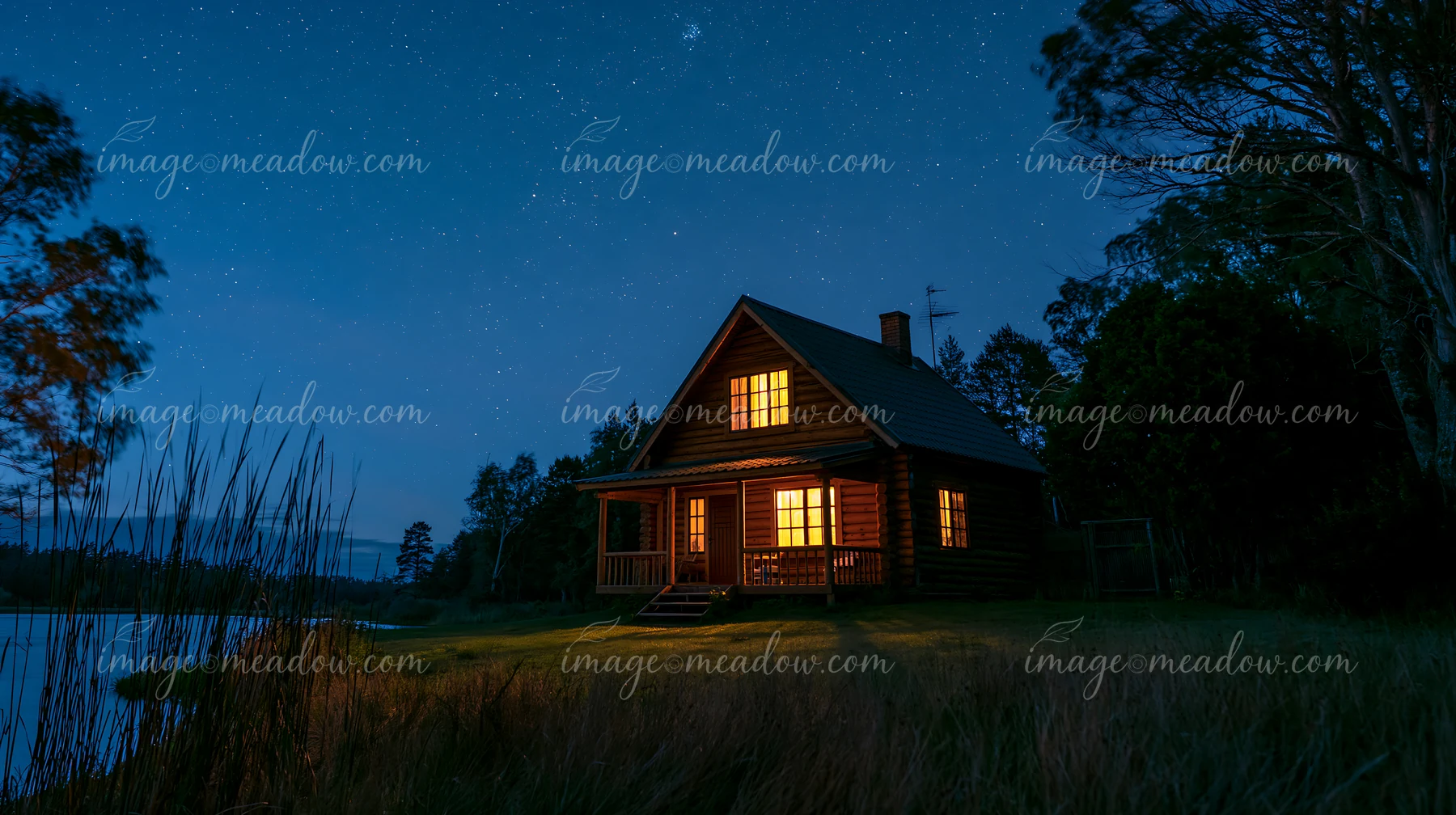 A cottage under stars with an open porch sits by a calm lake.