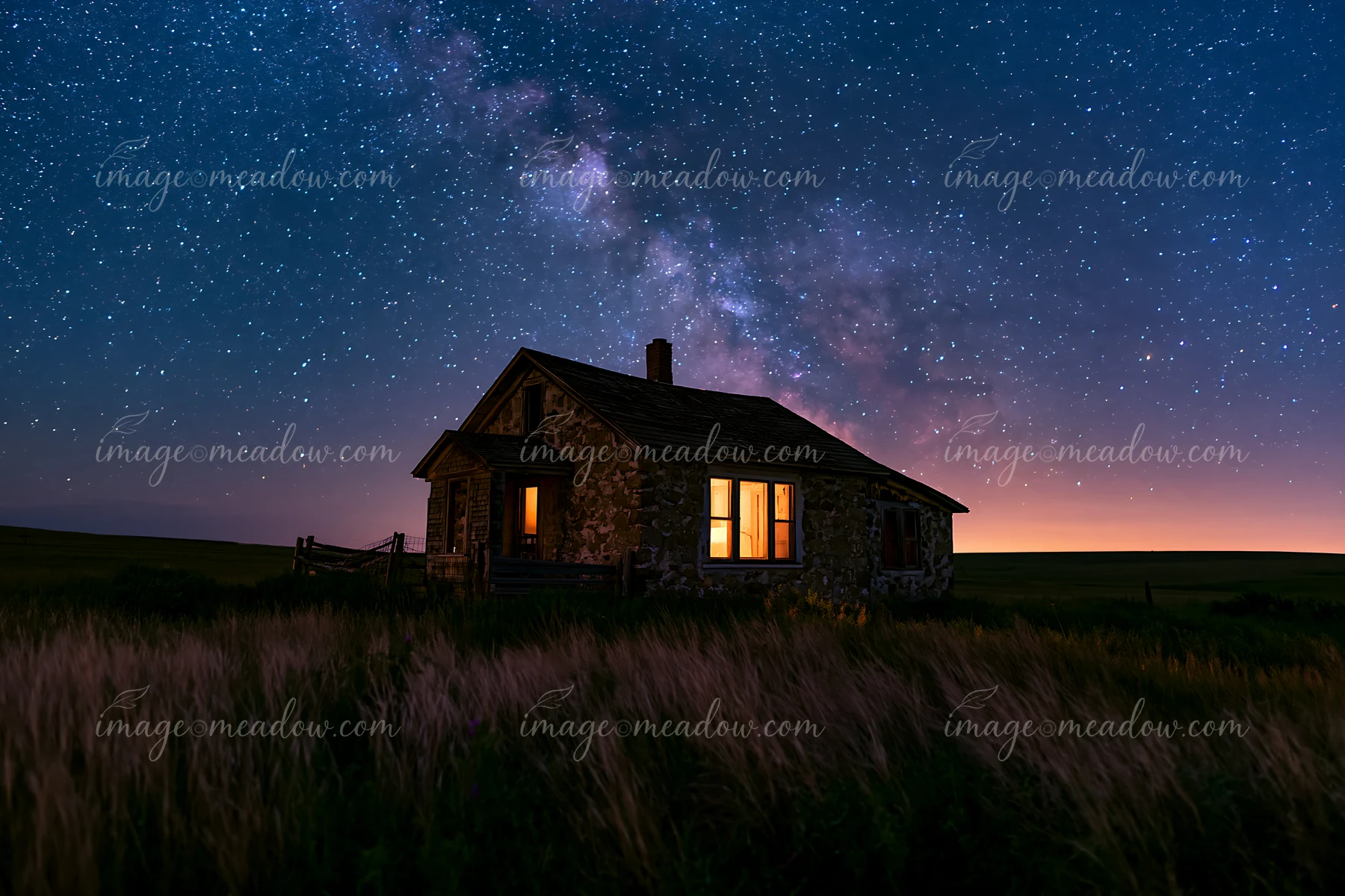 A country house stands in a rural setting under a clear night sky filled with stars and the milky way.