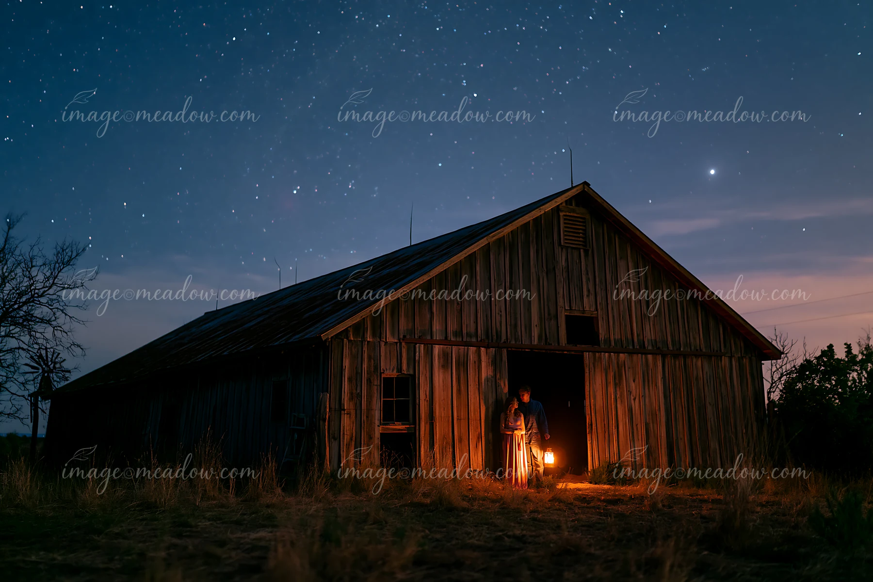 A couple holds a lantern under a starry sky near a wooden barn at night.
