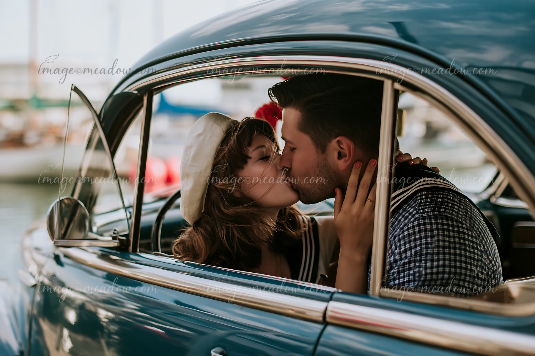 A couple is kissing inside a vintage car near a marina, surrounded by boats and a waterfront.