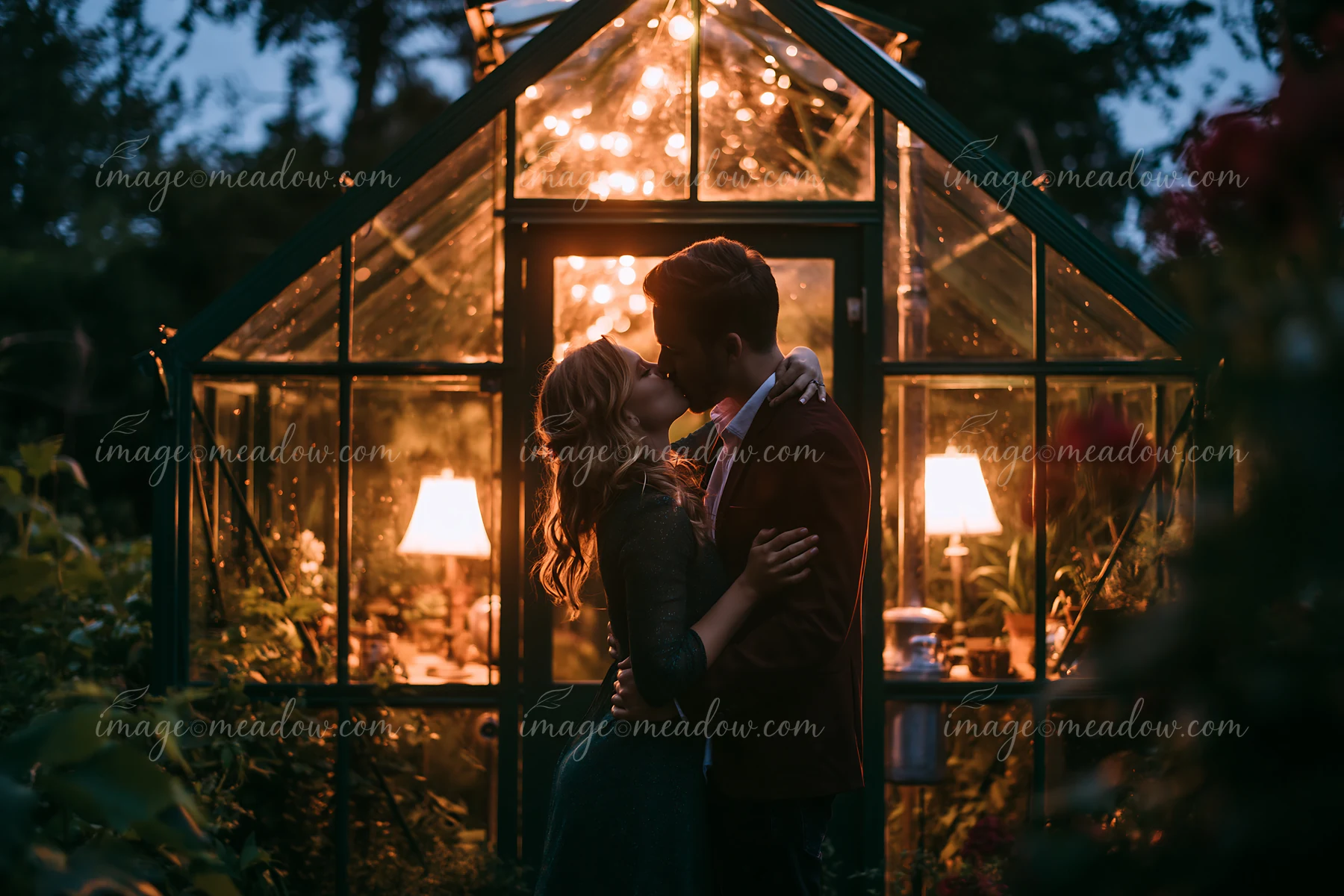 A couple kissing under stars during a romantic date in a garden.
