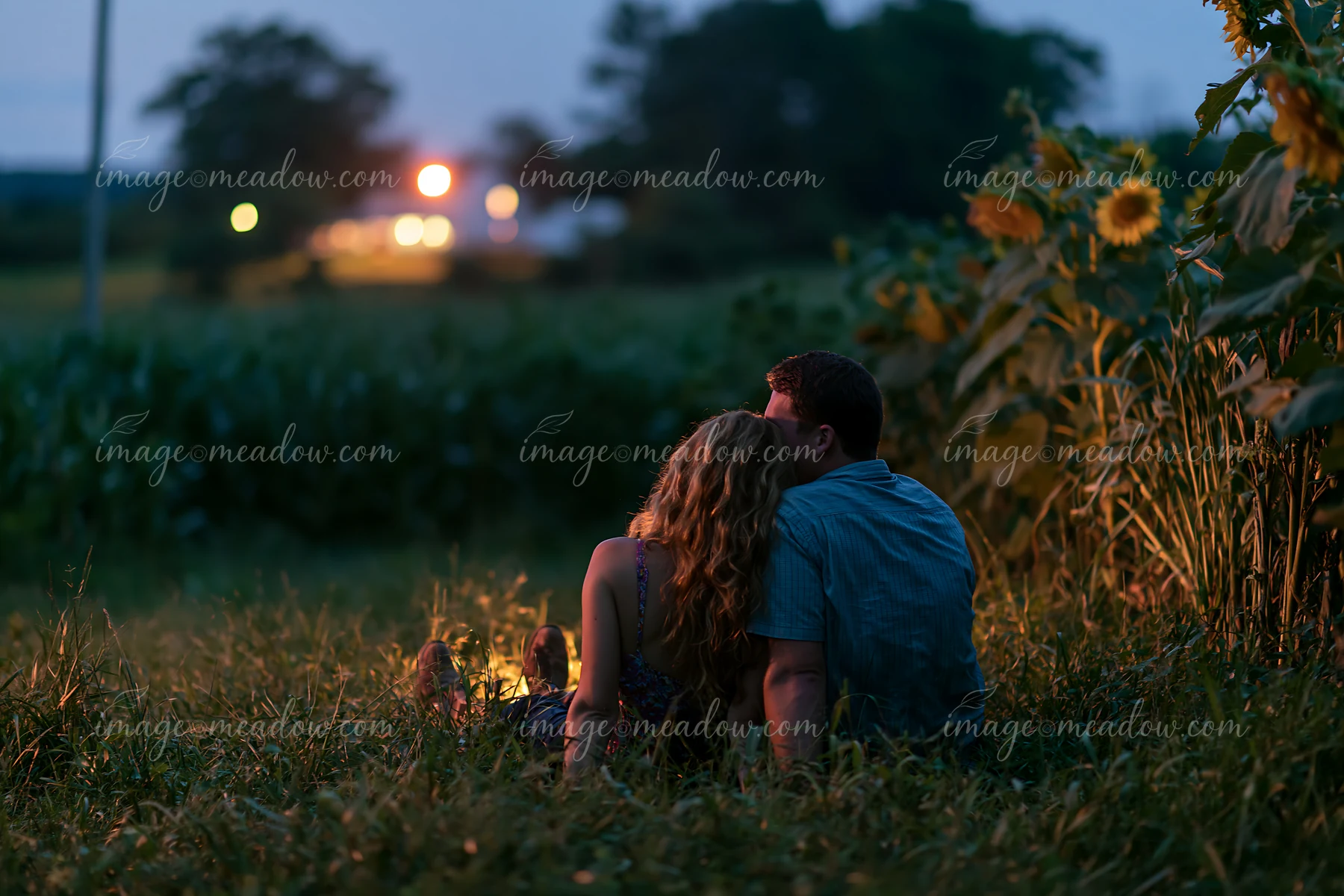 A couple lying in a field of grass at night shares a quiet moment together.