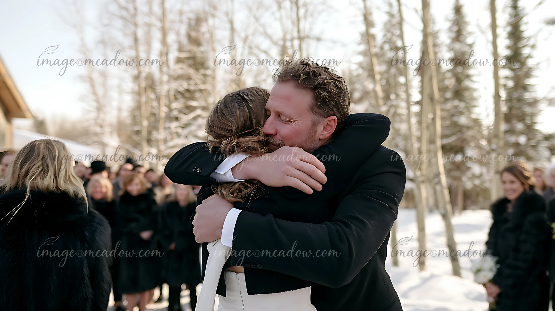 A couple shares an emotional embrace during their wedding ceremony in a snowy outdoor setting.