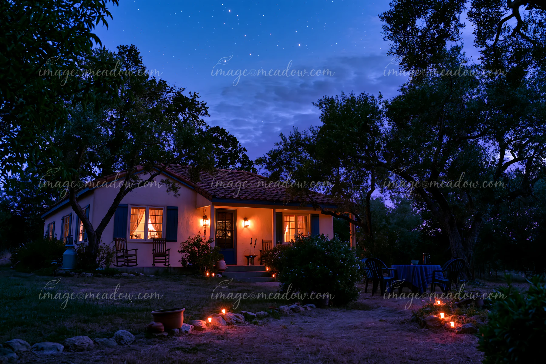 A cozy house sits under a sky filled with stars during blue hour.