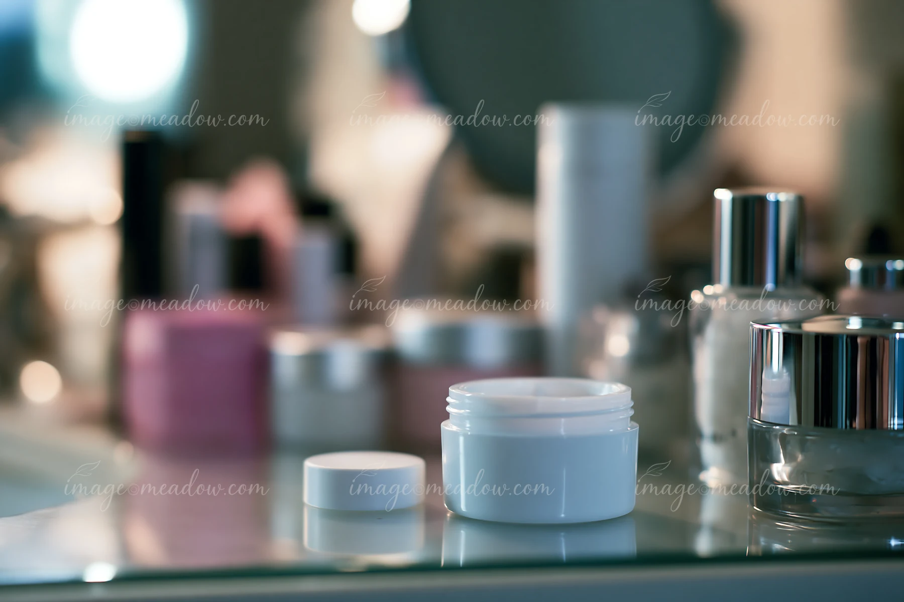 A cream dose is placed next to various unbranded cosmetic containers on a bathroom counter, showcasing a cluttered beauty routine setting with a mirror in the b