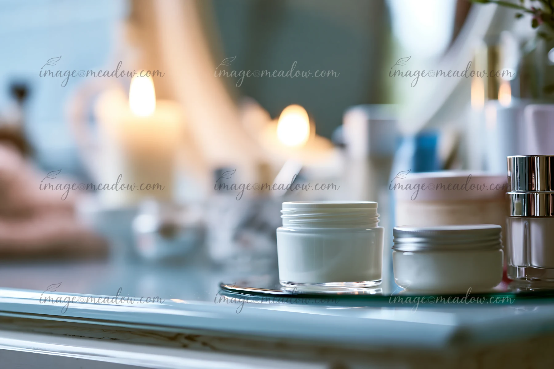 A cream dose sits next to unbranded cosmetic containers on a vanity, with soft candlelight in the background, creating a cozy atmosphere.