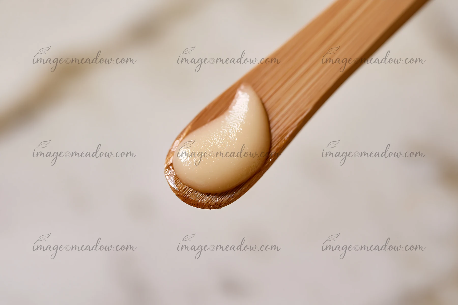 A creamy substance sits on a wooden stick, showcasing a matte texture.