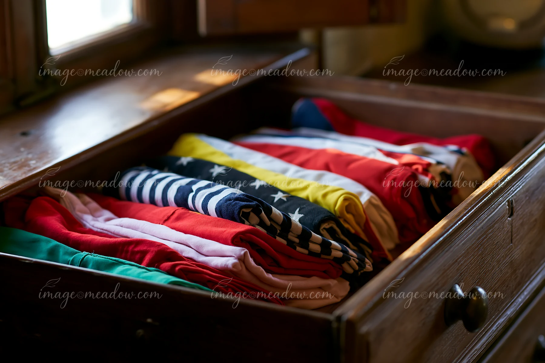 A drawer in a lighthouse museum contains neatly folded clothing in various colors and patterns.