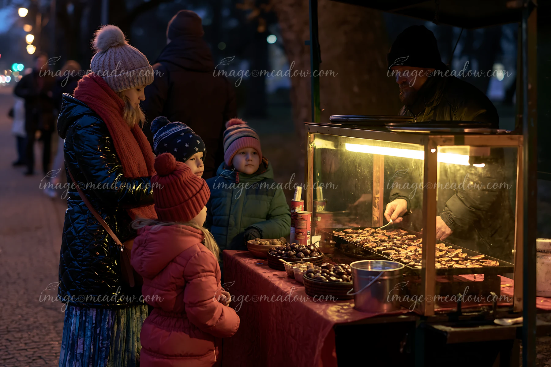 A family at food stalls looks at food options offered by a vendor.