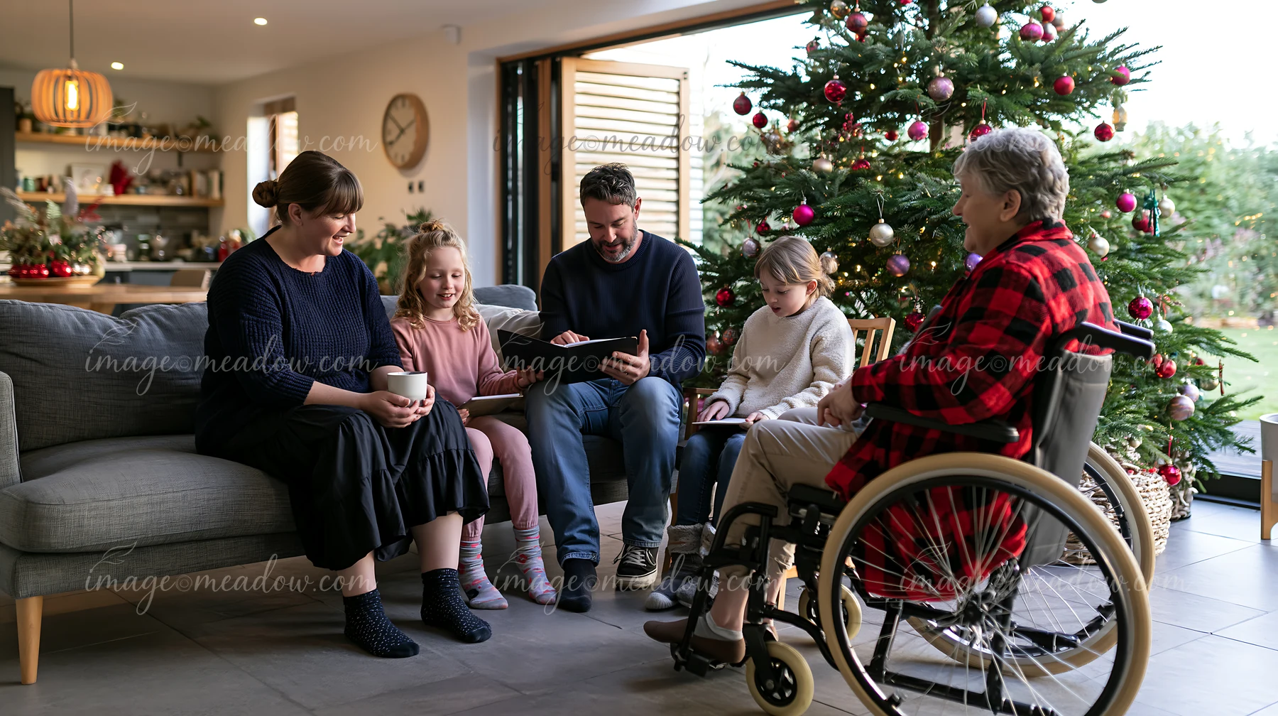 A family enjoys time together indoors near a decorated Christmas tree.