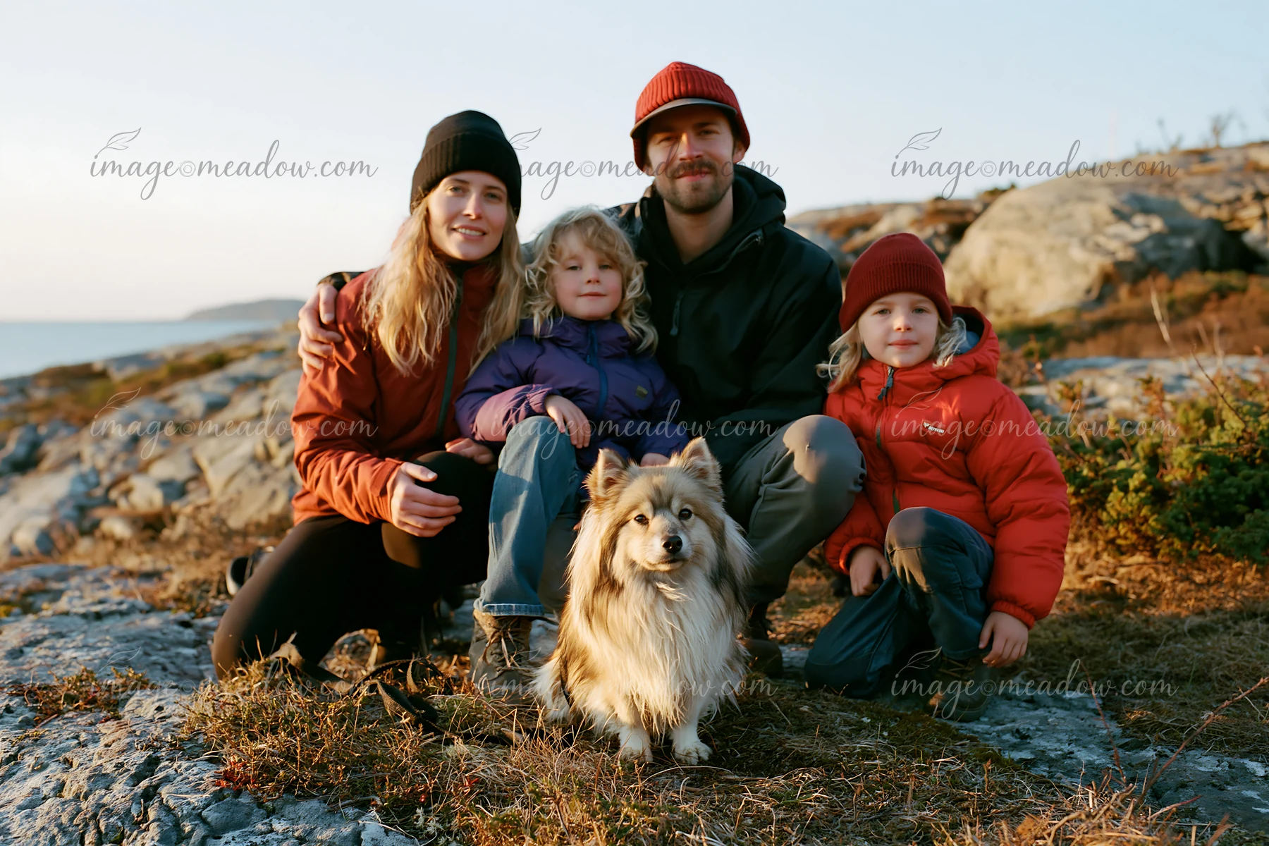 A family gathers on a rocky outdoor setting with their rare dog breed.