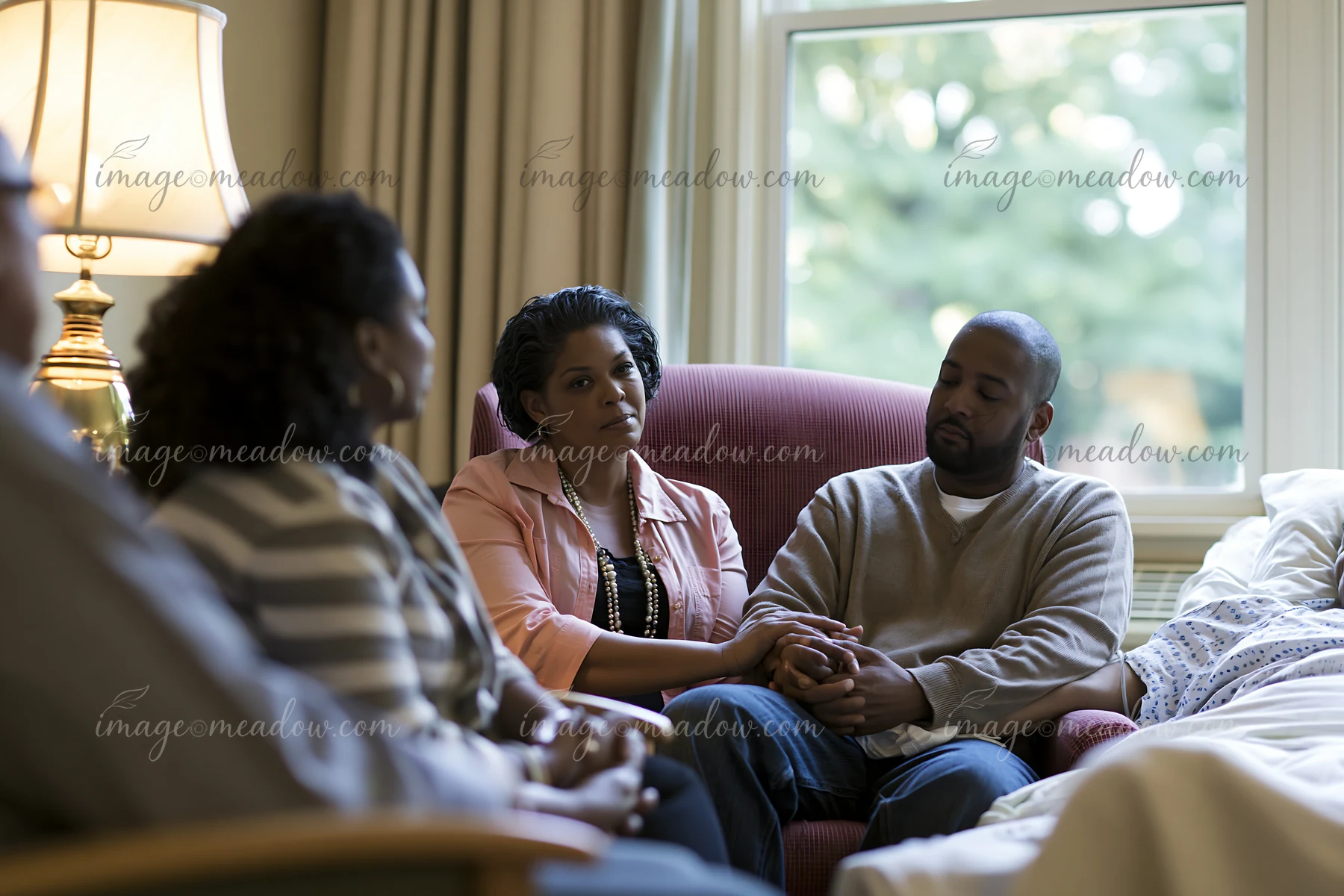 A family is seated together in a room beside a hospice patient.