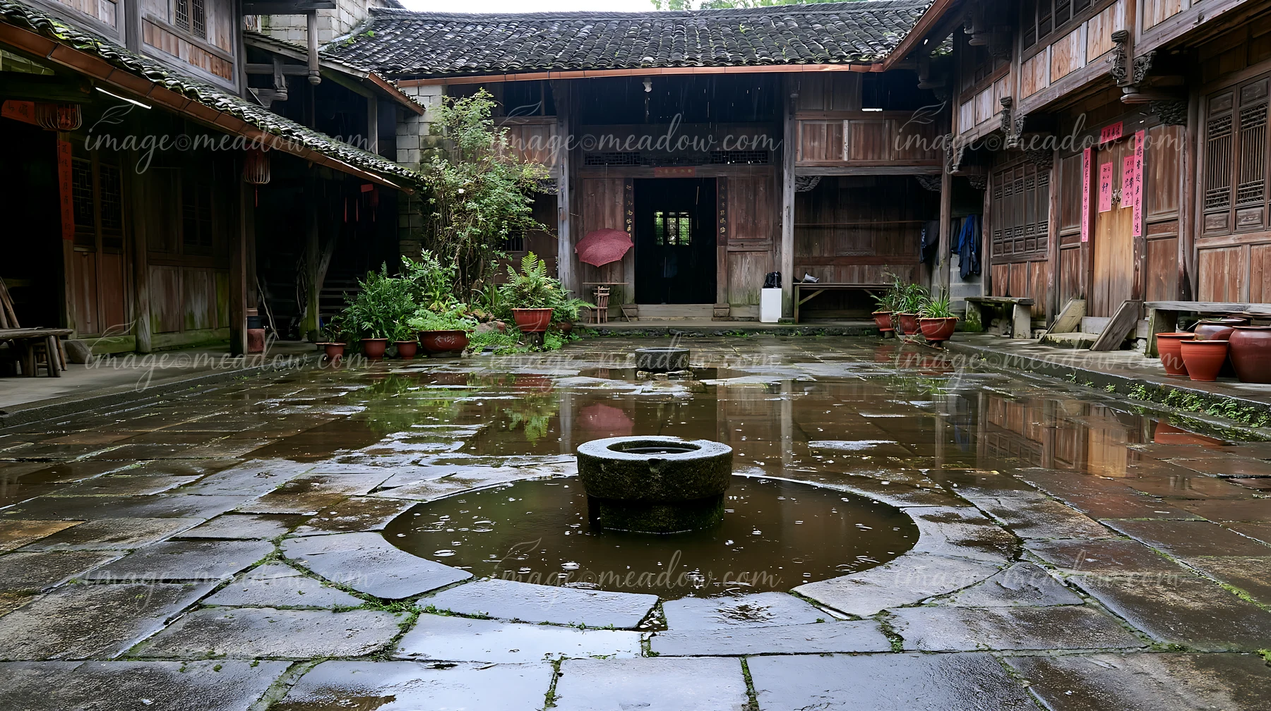 A farmhouse courtyard with well features an open space filled with stone pathways and planters around.
