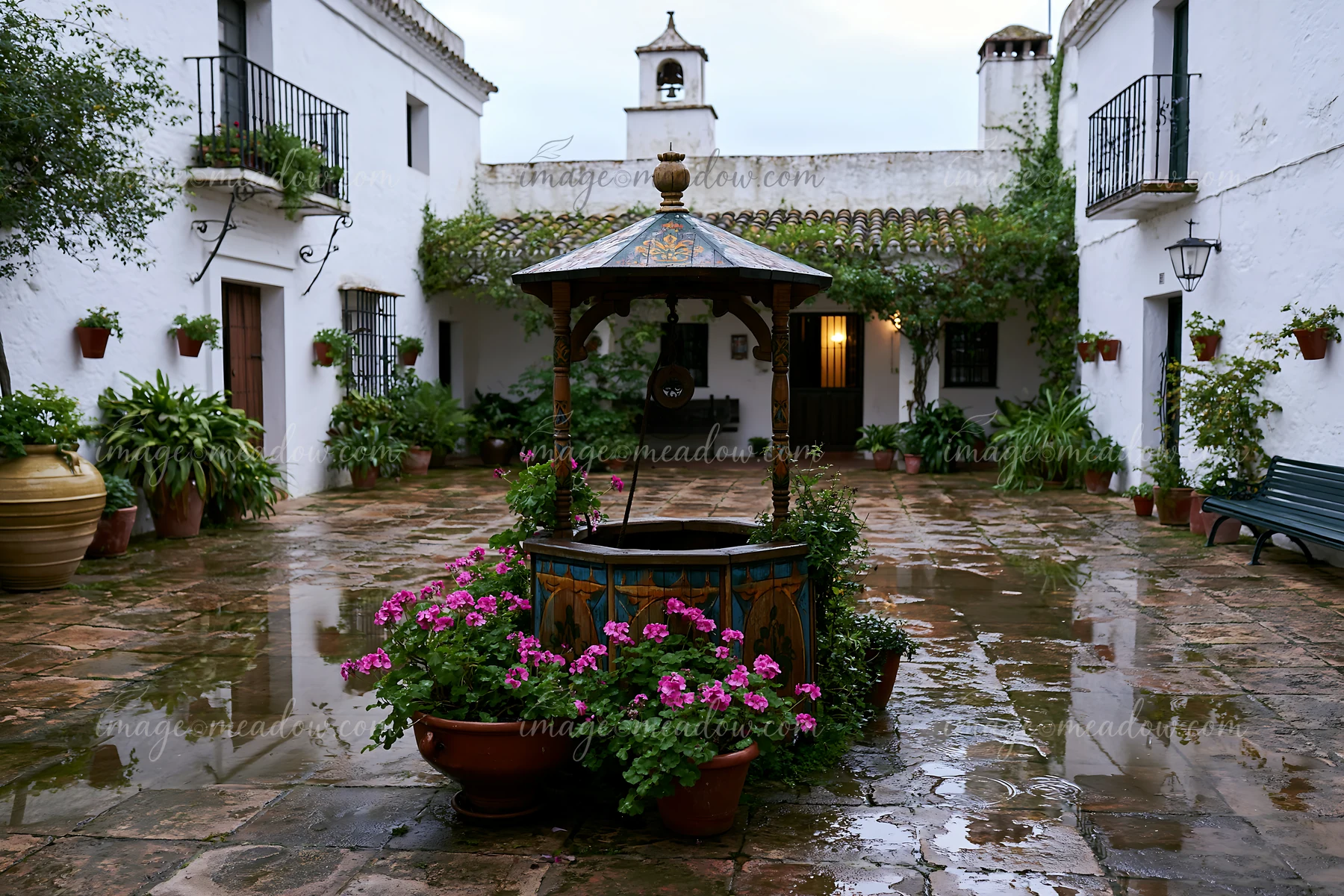 A farmhouse courtyard with well features stone tiles and potted plants.