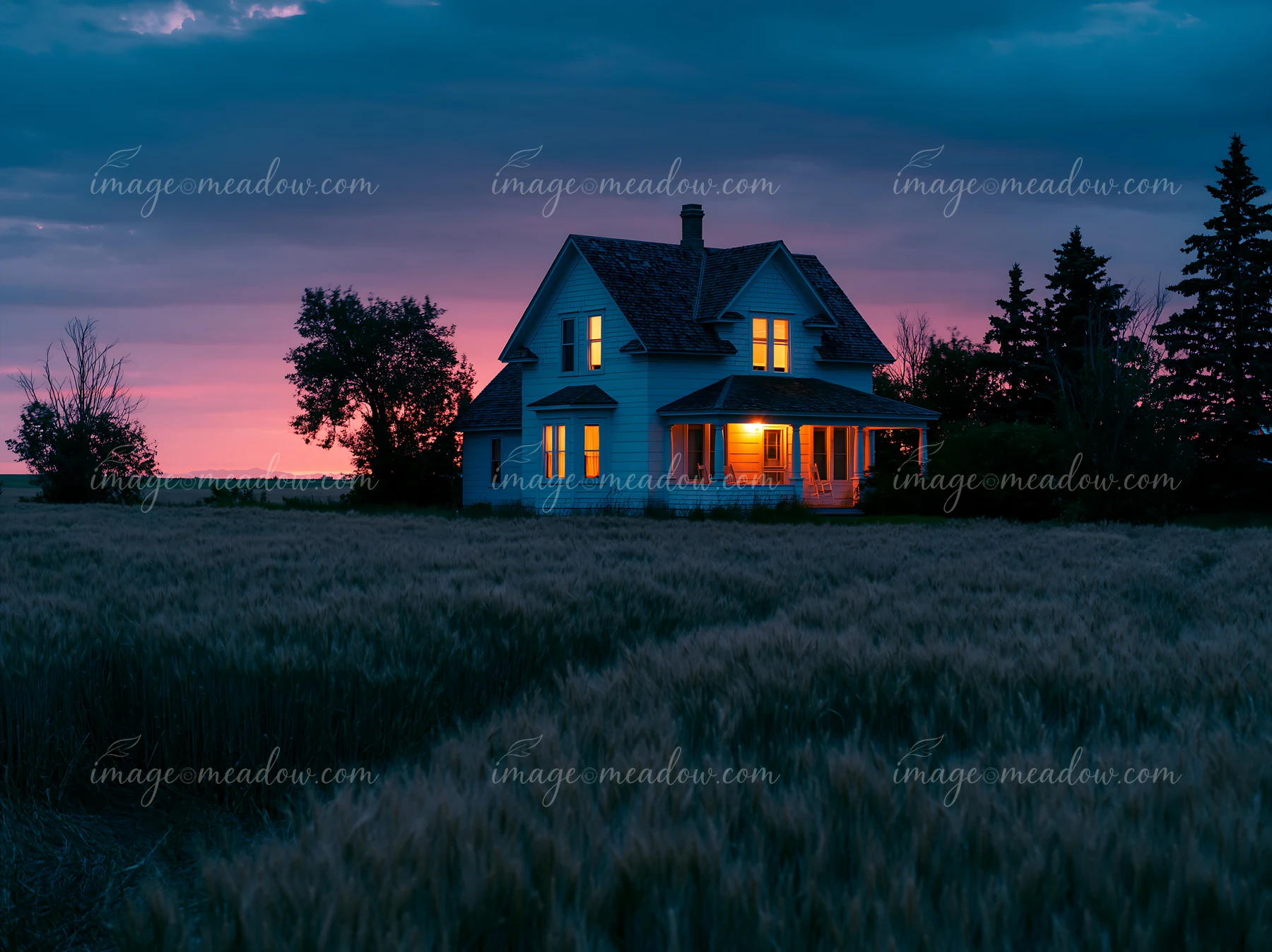 A farmhouse surrounded by wheat fields stands against a colorful sunset.