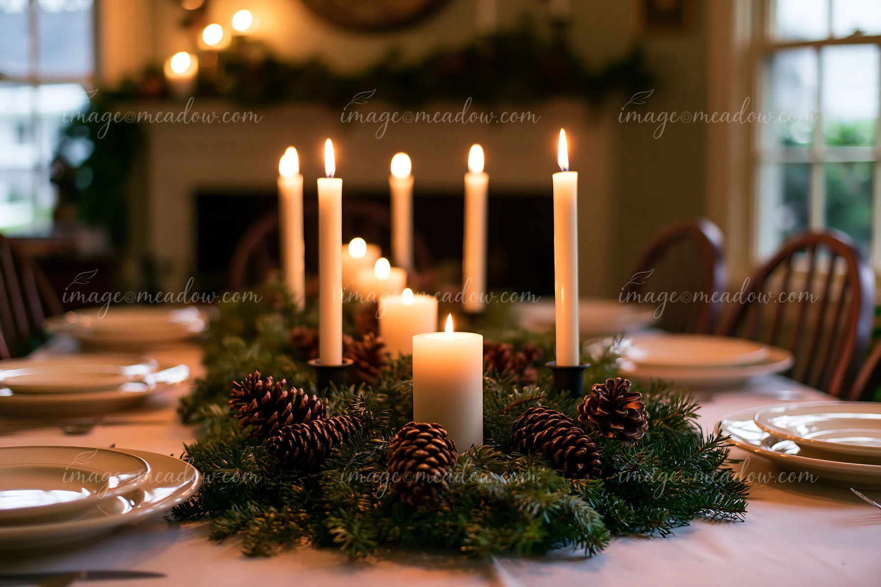 A festive Christmas centerpiece features candles and pinecones on a dining table, creating a warm atmosphere in a decorated room.