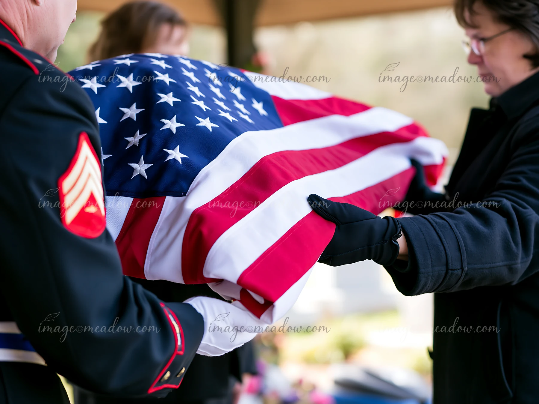 A folded American flag is presented to a grieving family member during a memorial service.