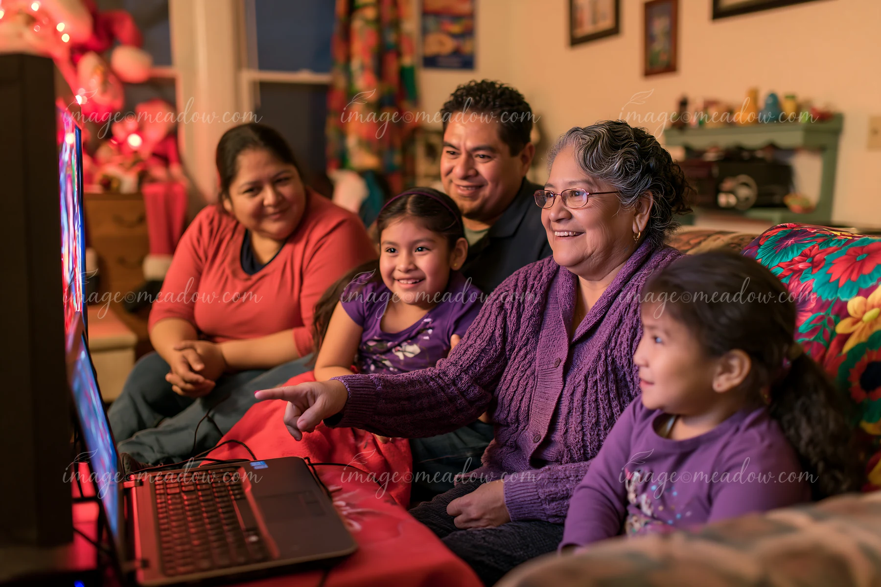 A group gathers in a warm living room, focused on a screen while watching a movie.