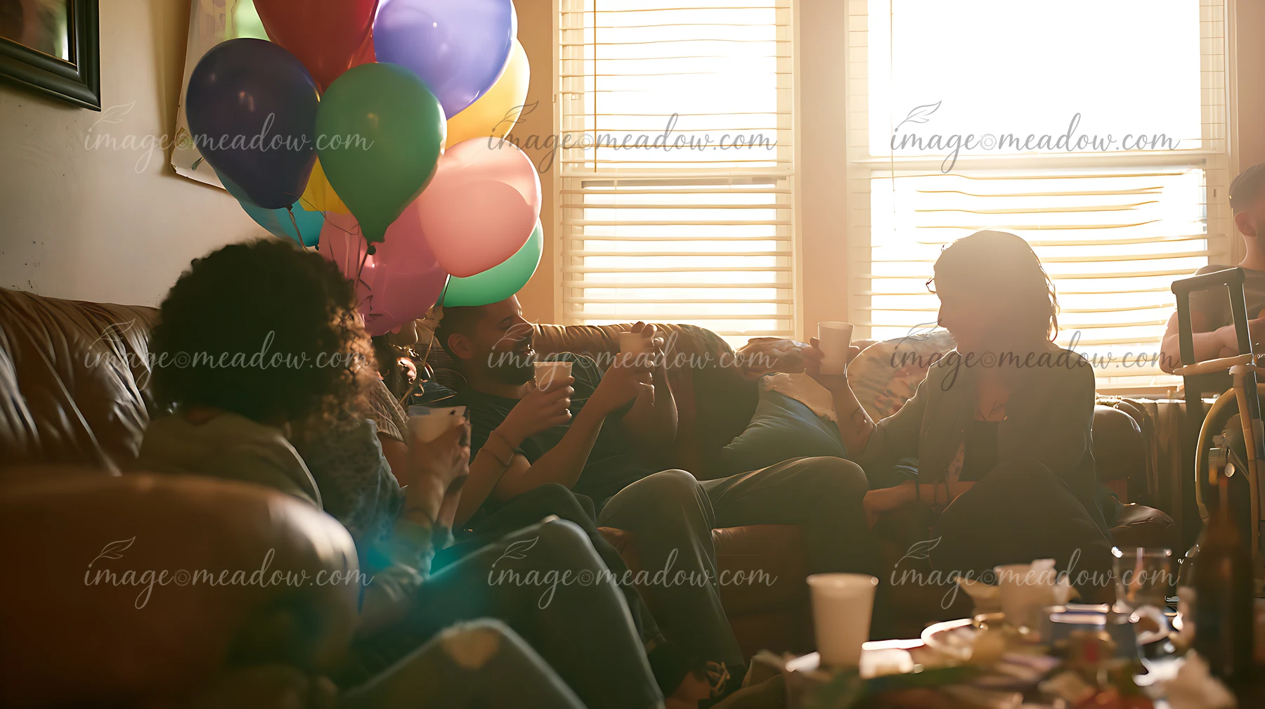 A group of friends sit on a couch in a living room filled with birthday balloons.
