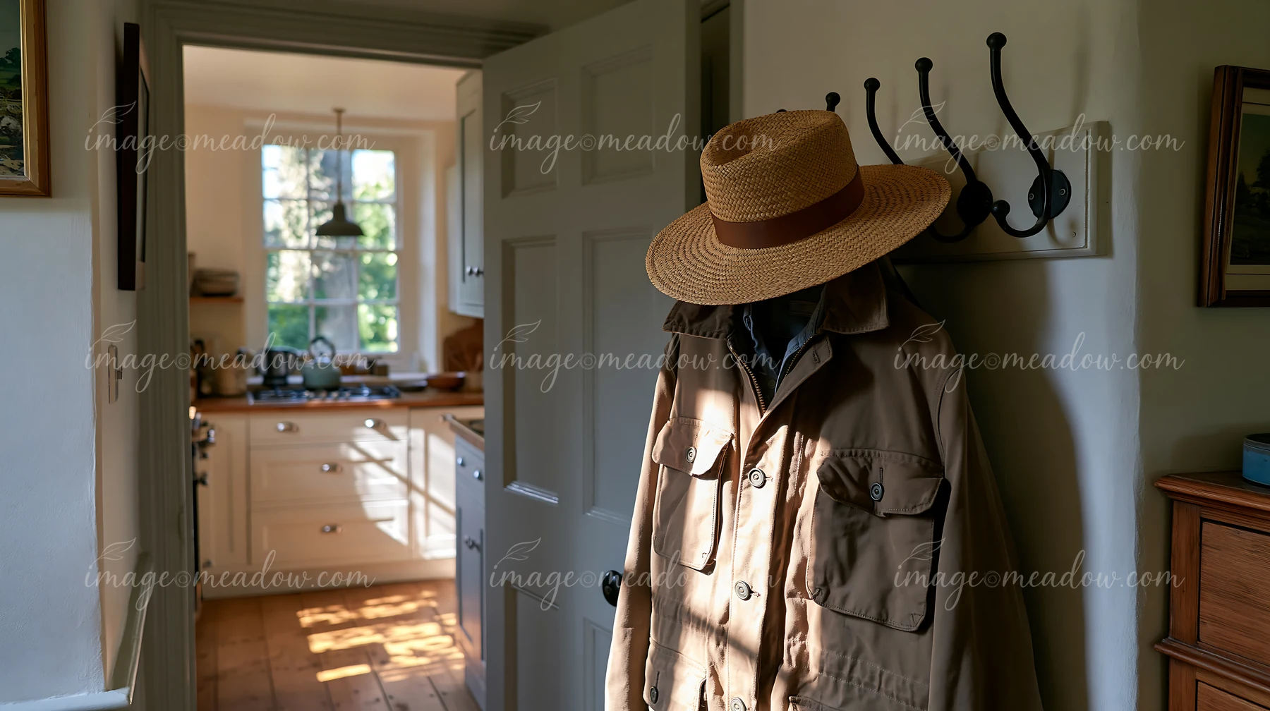 A hallway in a country house features coat hooks with a jacket and straw hat hanging.