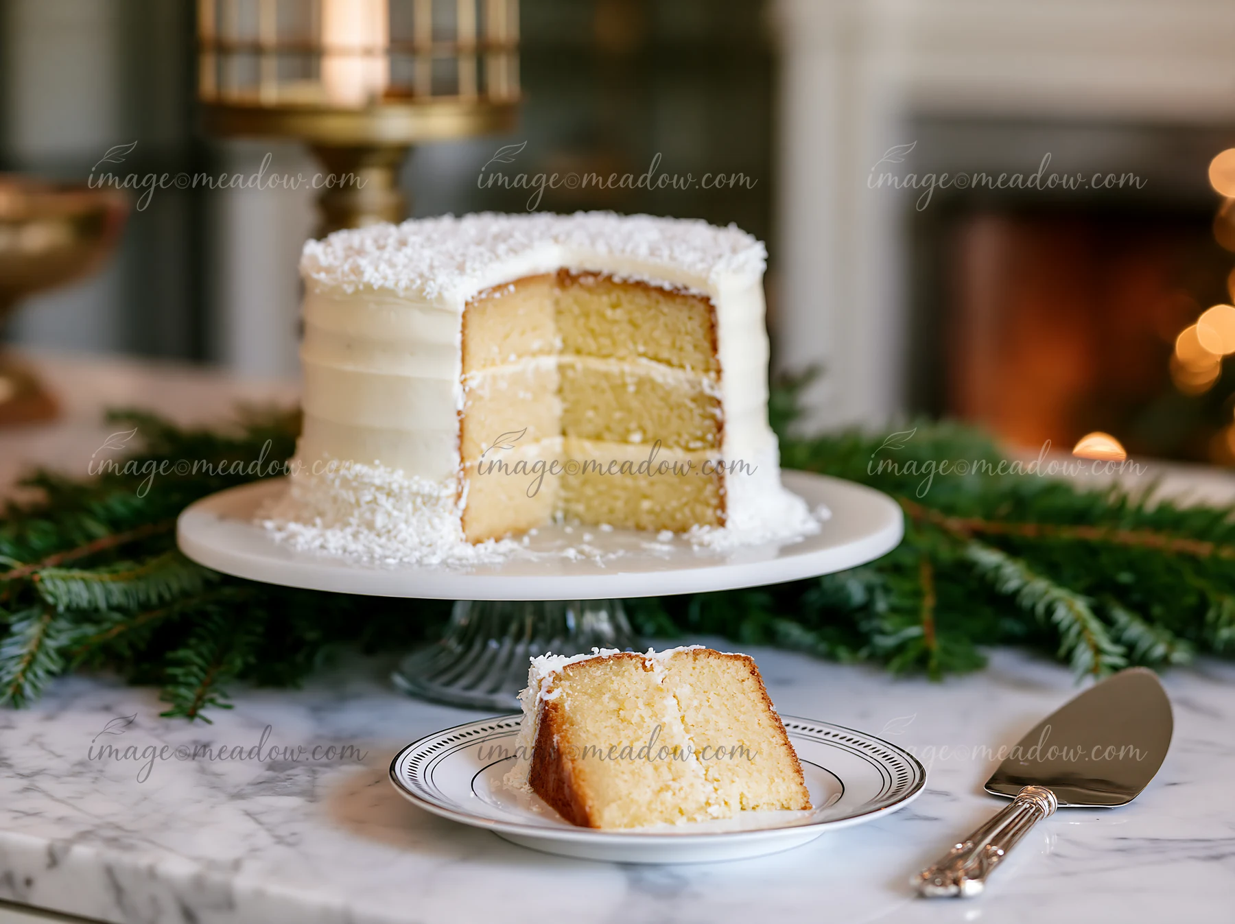 A holiday cake sits on a marble countertop surrounded by green pine branches.