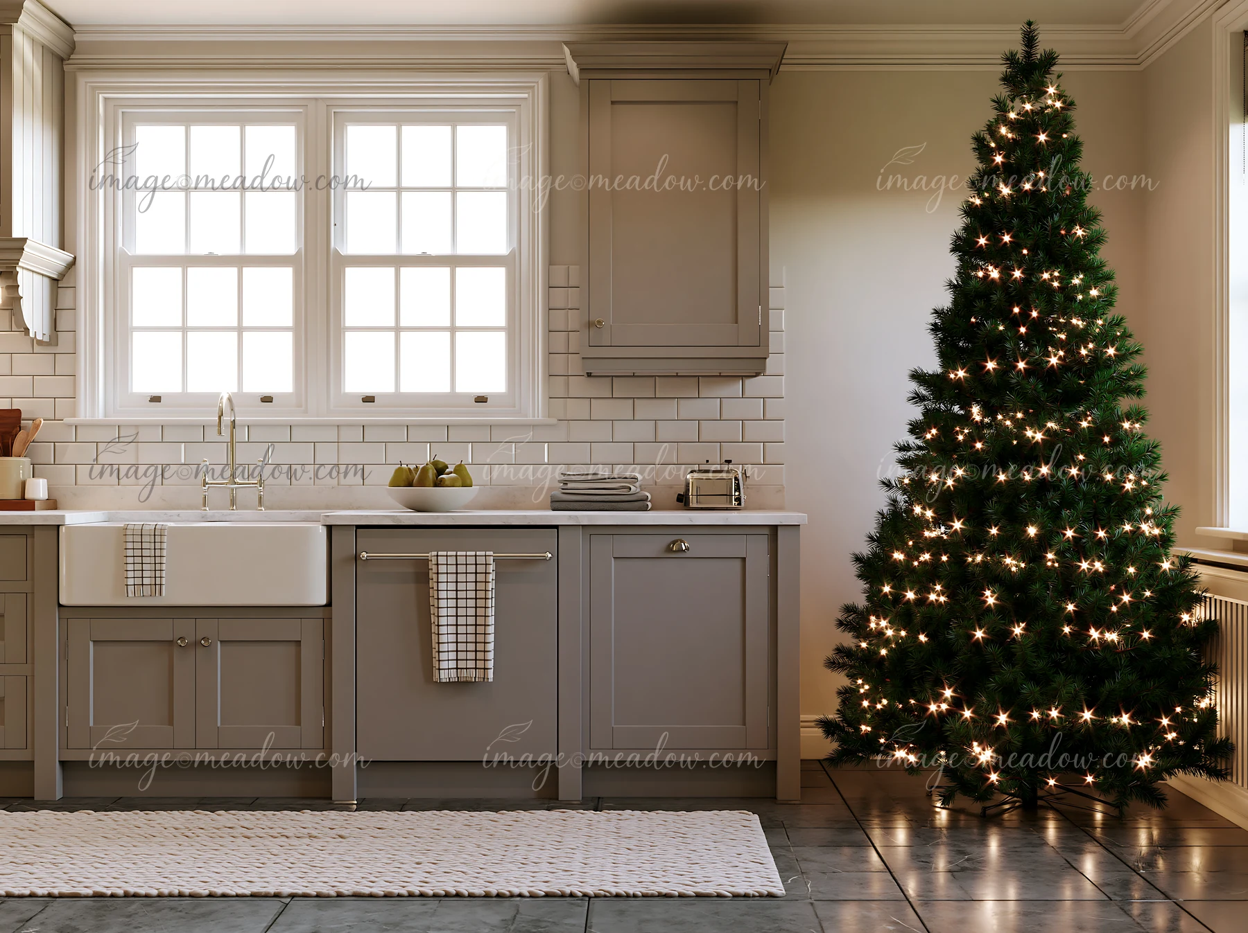 A holiday decorated kitchen showcases an illuminated Christmas tree beside a sink and countertops.