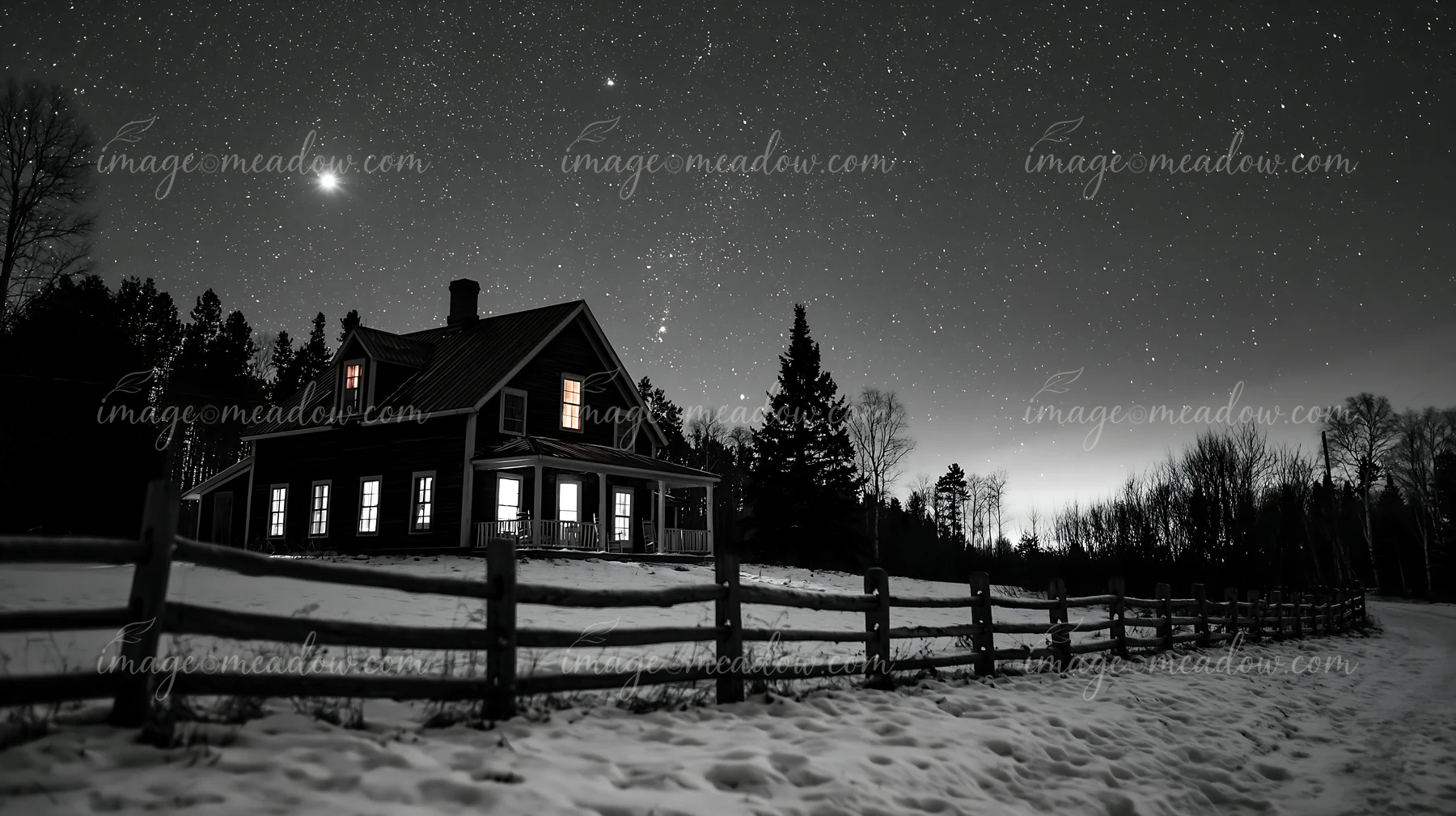 A house stands in the snow with bright windows, surrounded by trees.