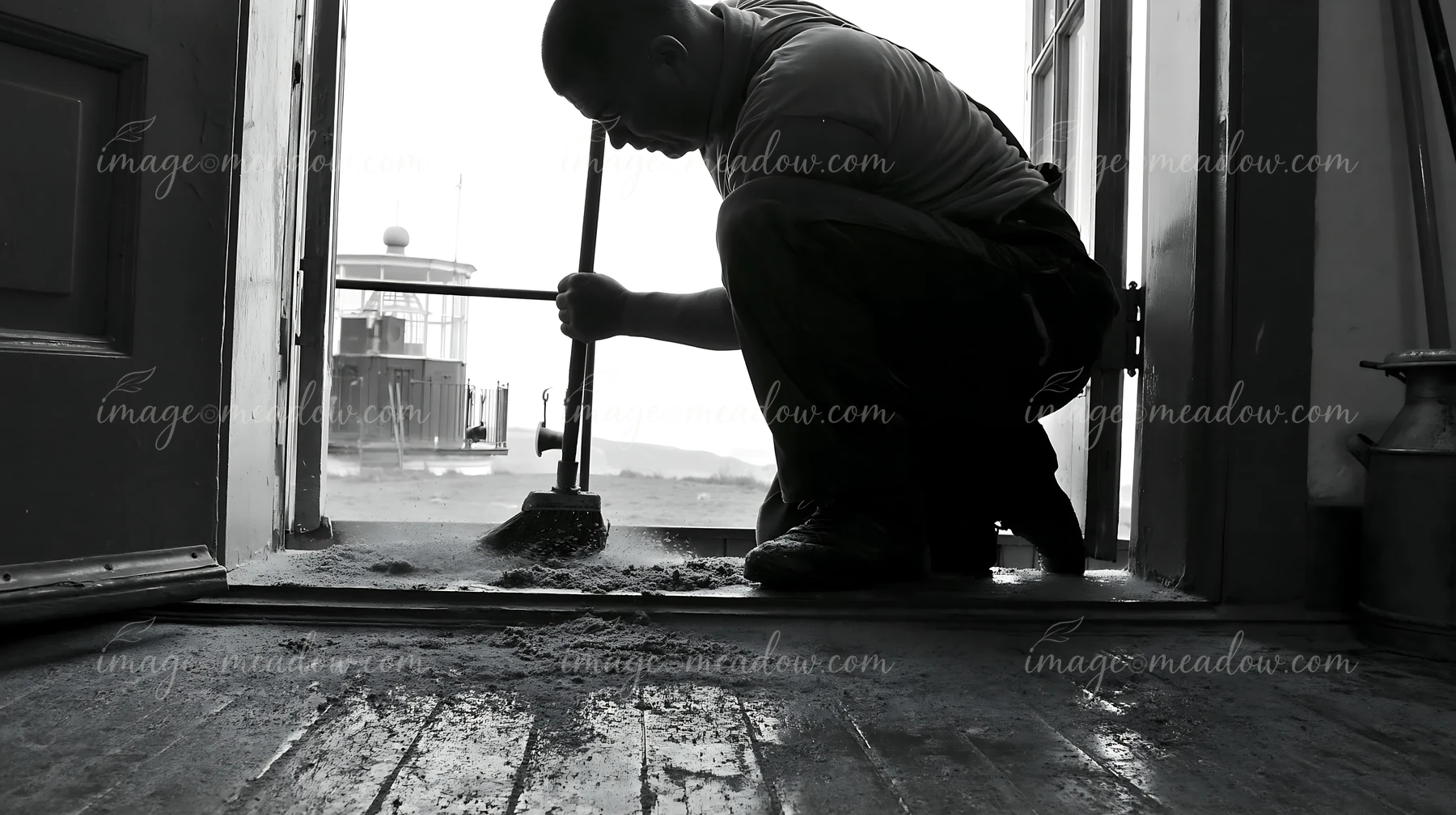 A lighthouse maintenance worker at work cleans the entrance area of a lighthouse.