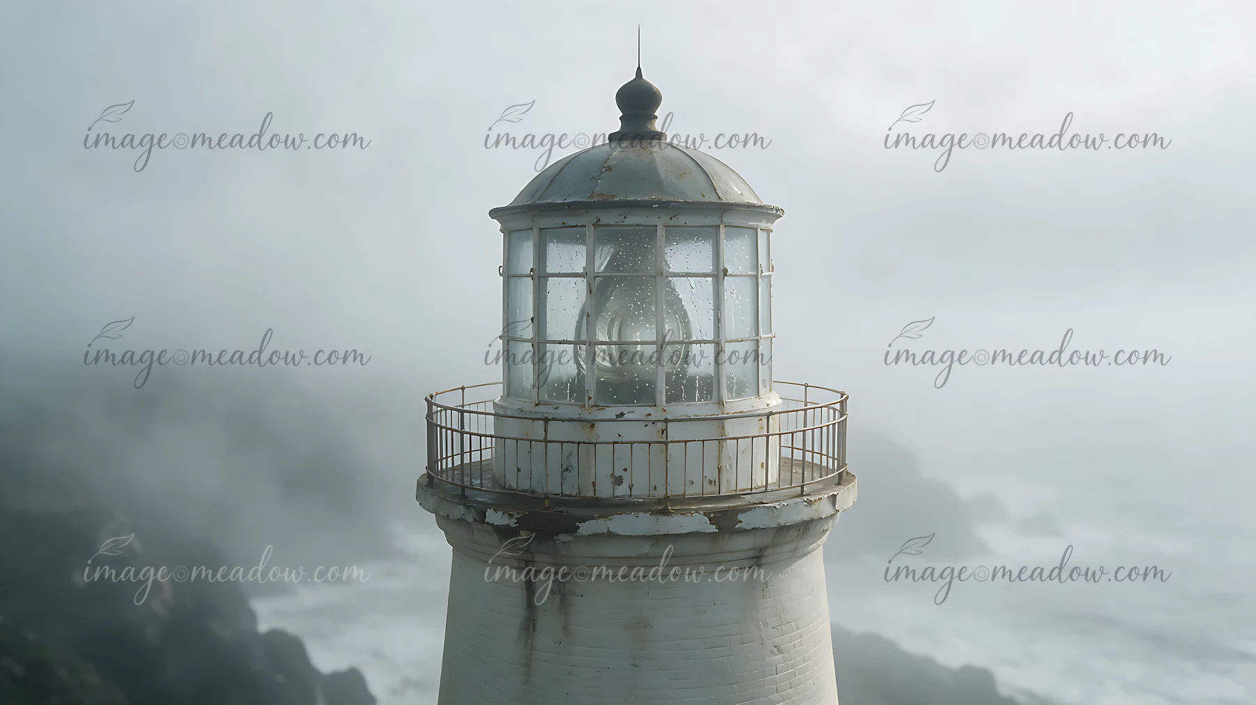 A lighthouse stands tall amidst heavy ocean fog.