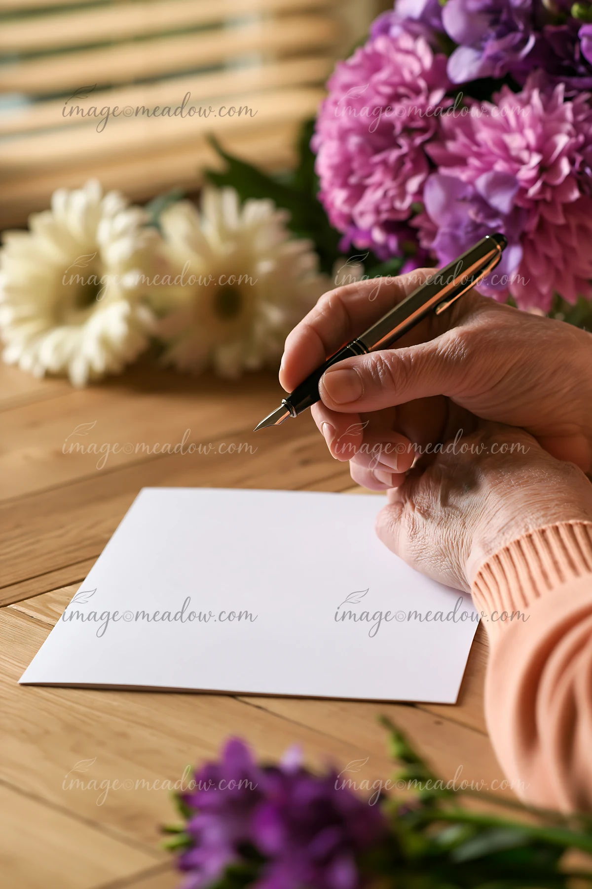 A Parkinson's patient holding a pen prepares to write on a blank sheet of paper surrounded by fresh flowers.