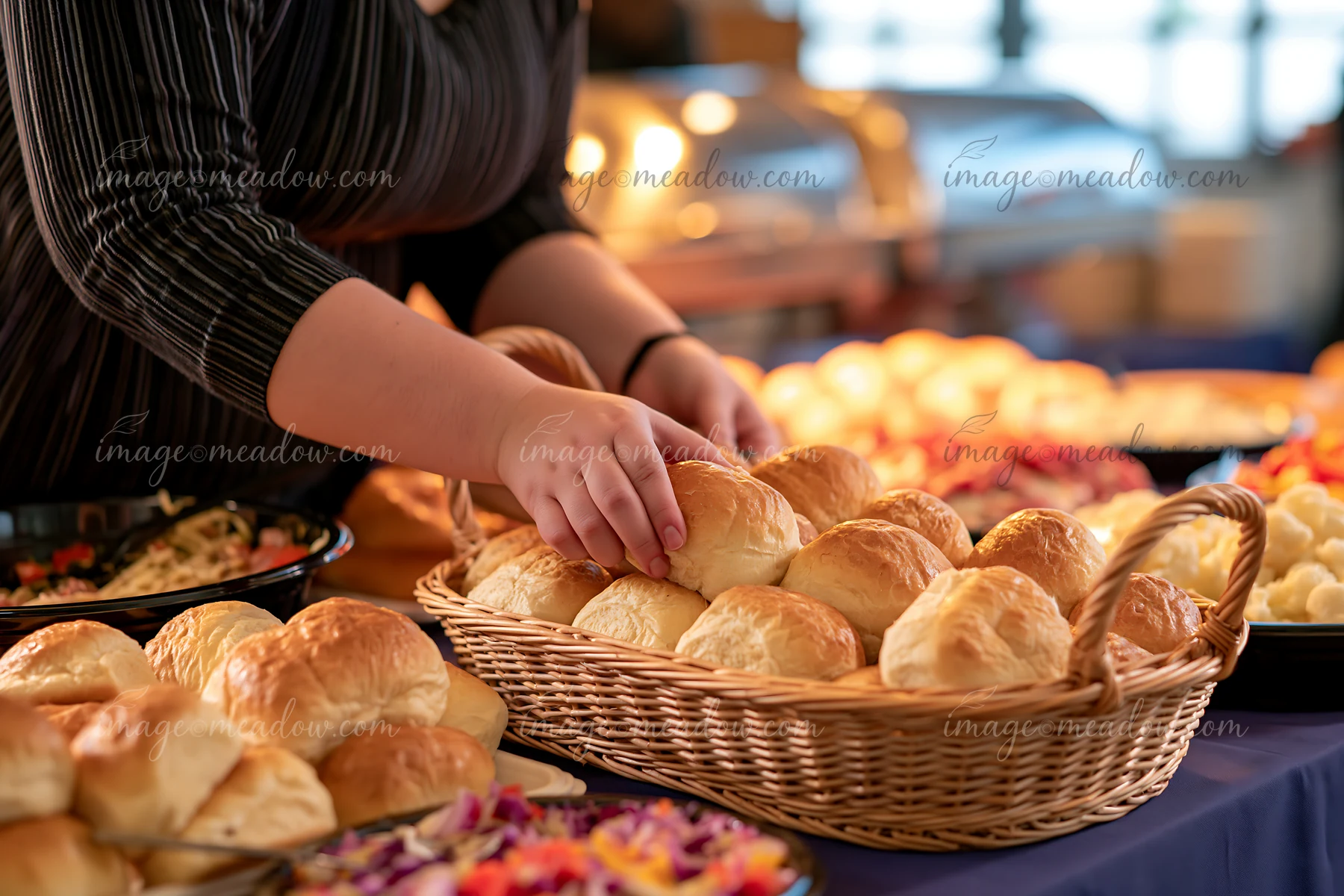 A person is picking fresh bread rolls from a basket at a buffet during a charity event.
