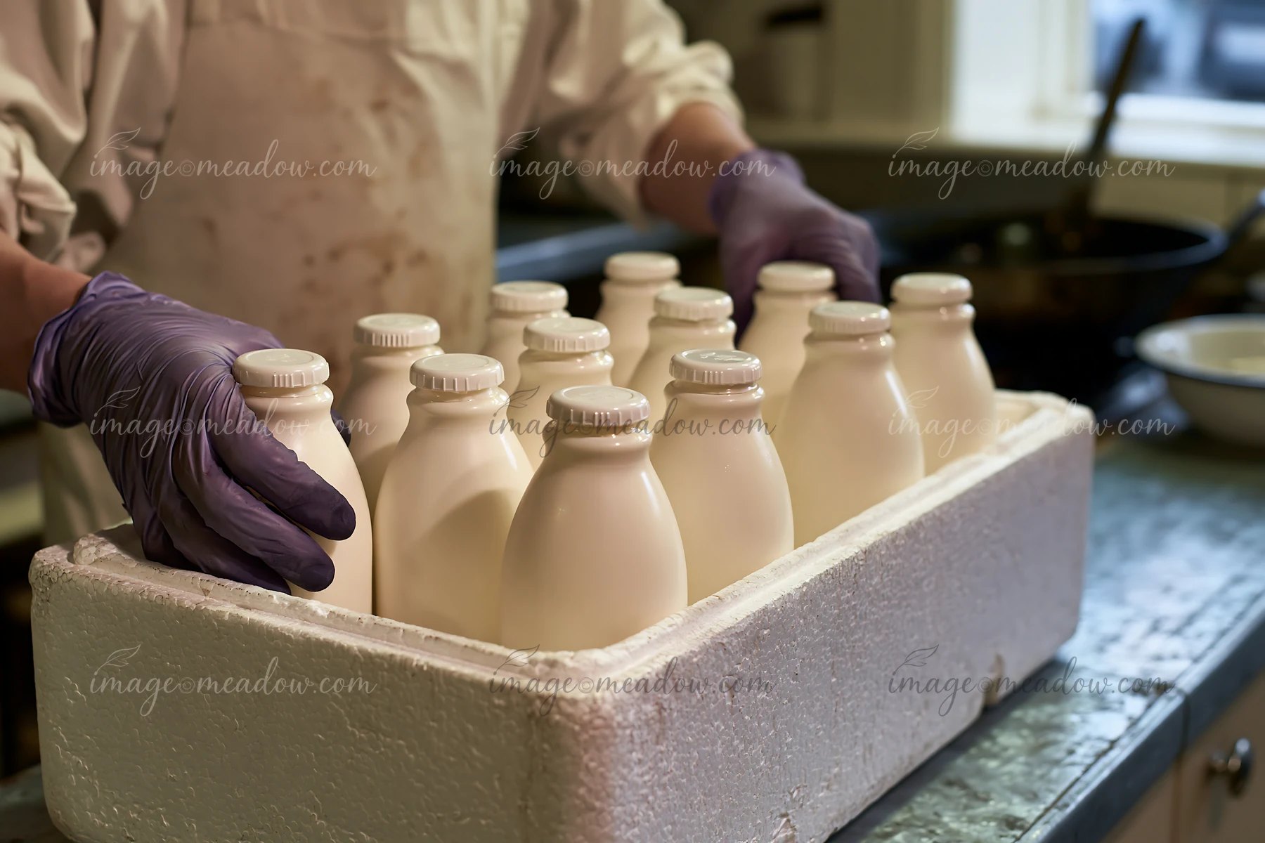 A person places milk bottles in an insulated delivery box on a work surface, preparing for delivery.