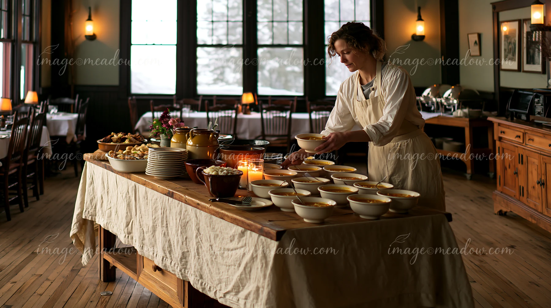 A person serves food from a rustic wooden buffet with a linen tablecloth in a cozy restaurant.