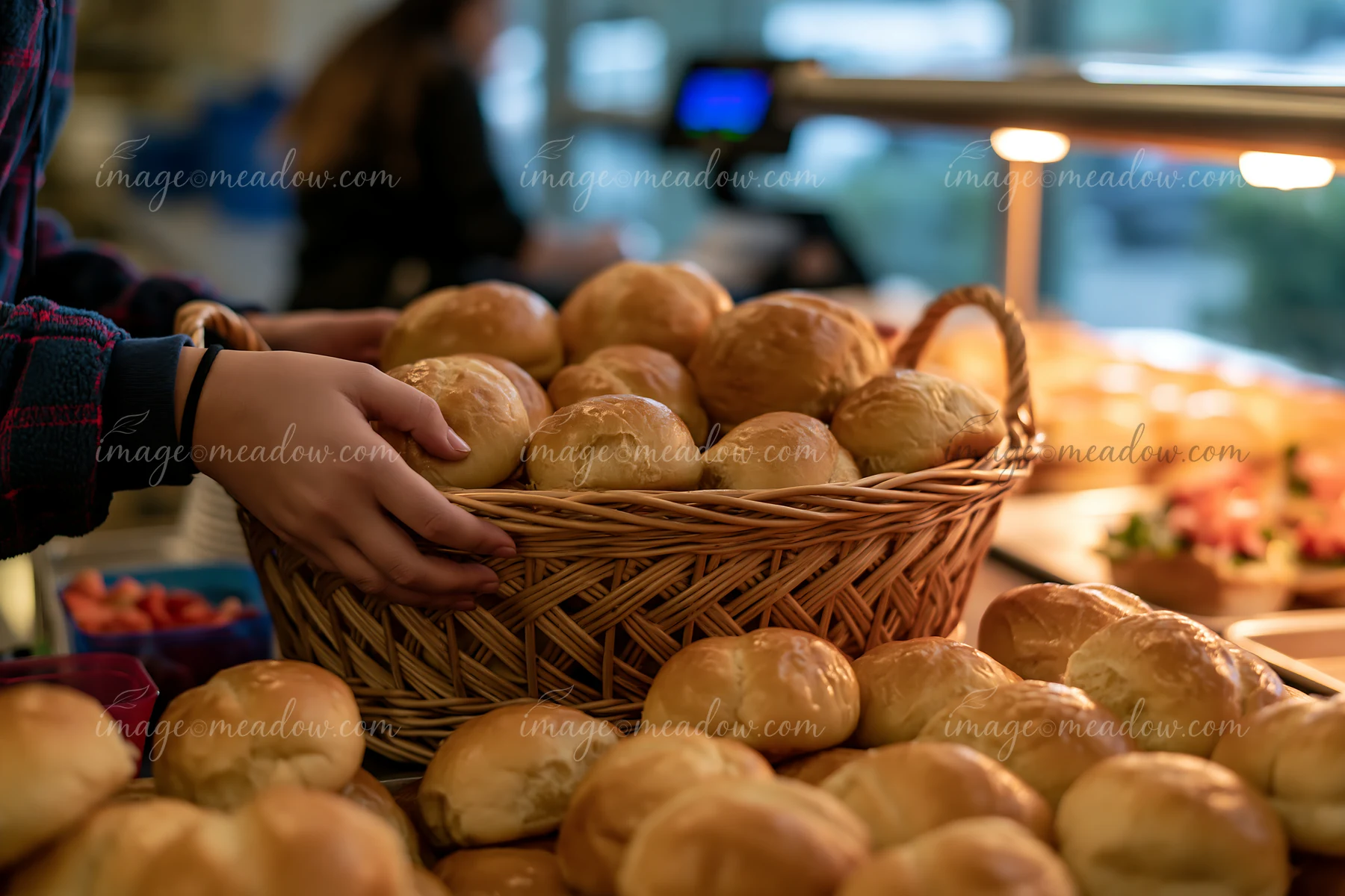 A person serves fresh rolls from a basket at a charity event buffet.
