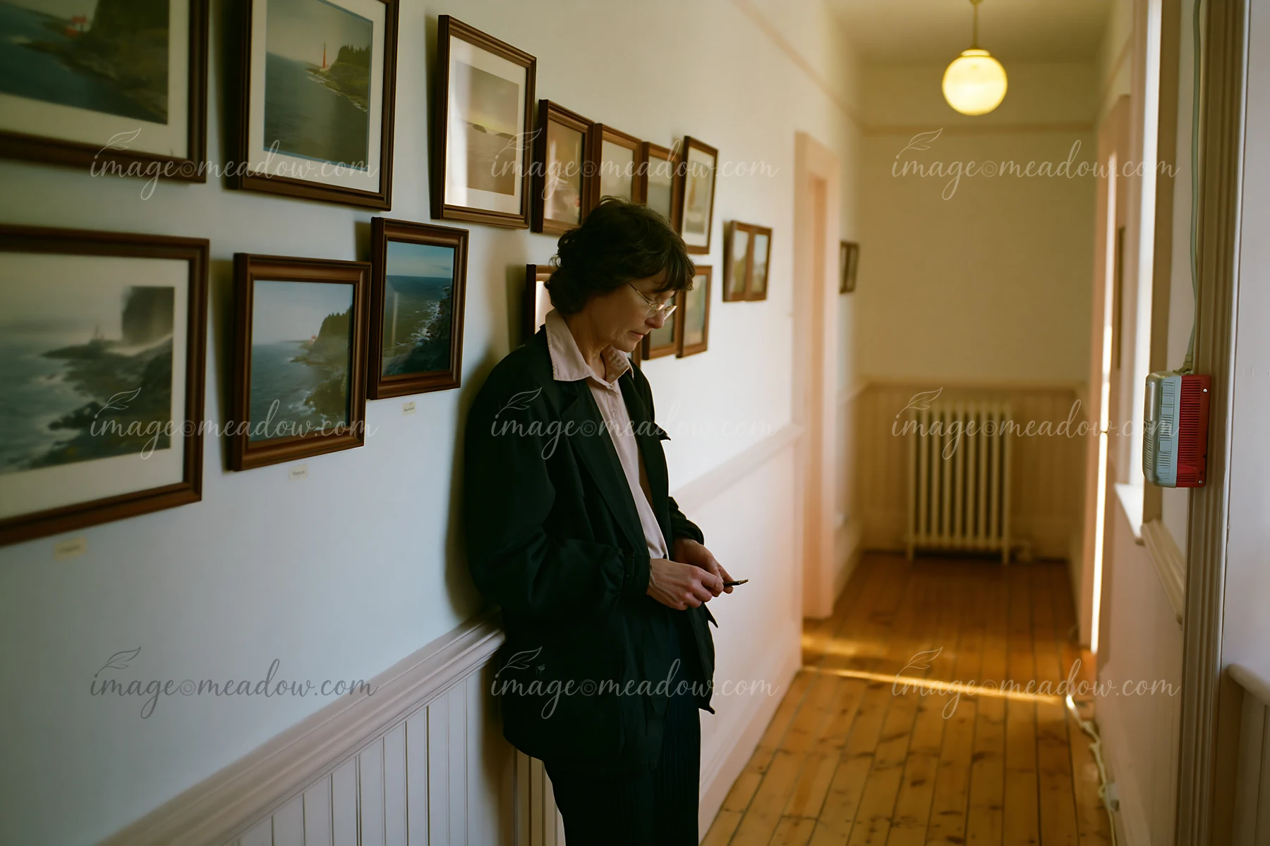 A person stands in a hallway of a lighthouse museum interior, gazing at their phone.