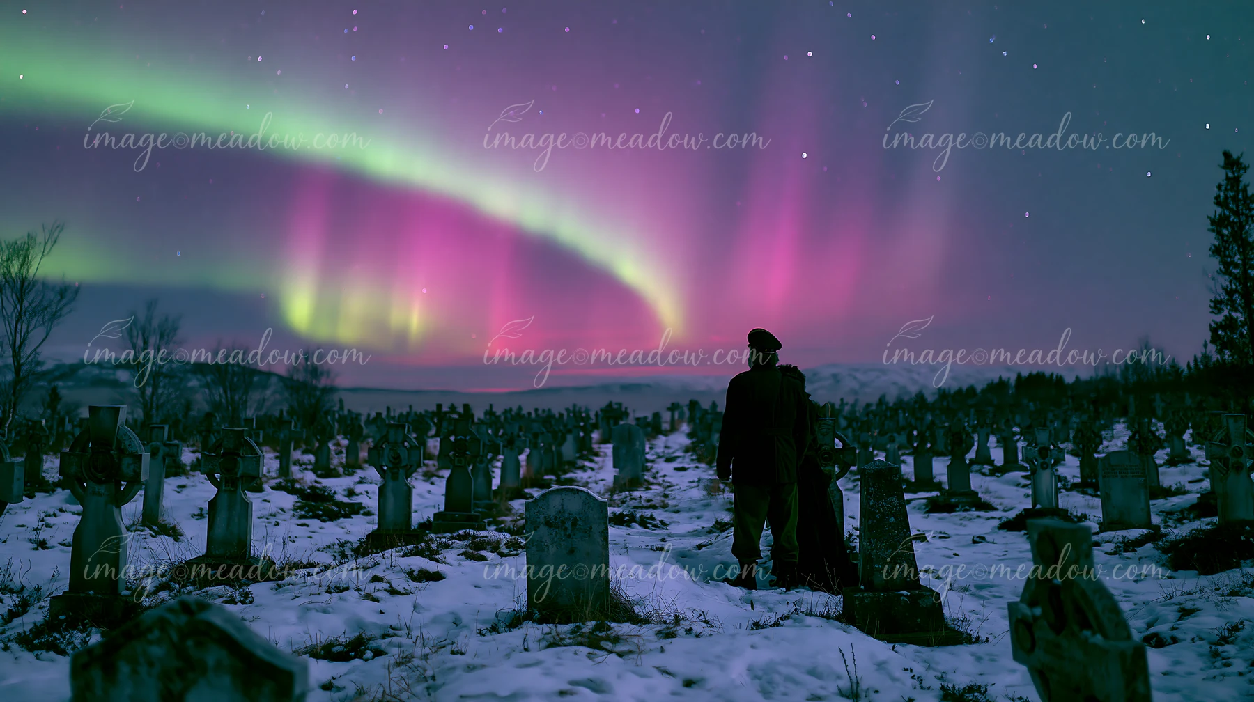 A person stands silently in a military cemetery as the northern lights illuminate the sky.