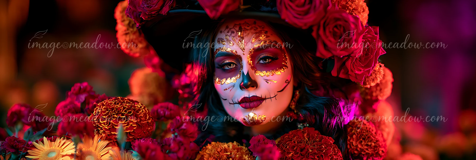 A person wears intricate skull makeup surrounded by bright flowers.