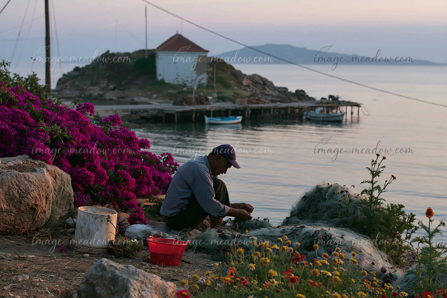 A person works on the rocks surrounded by colorful flowers on a remote island.