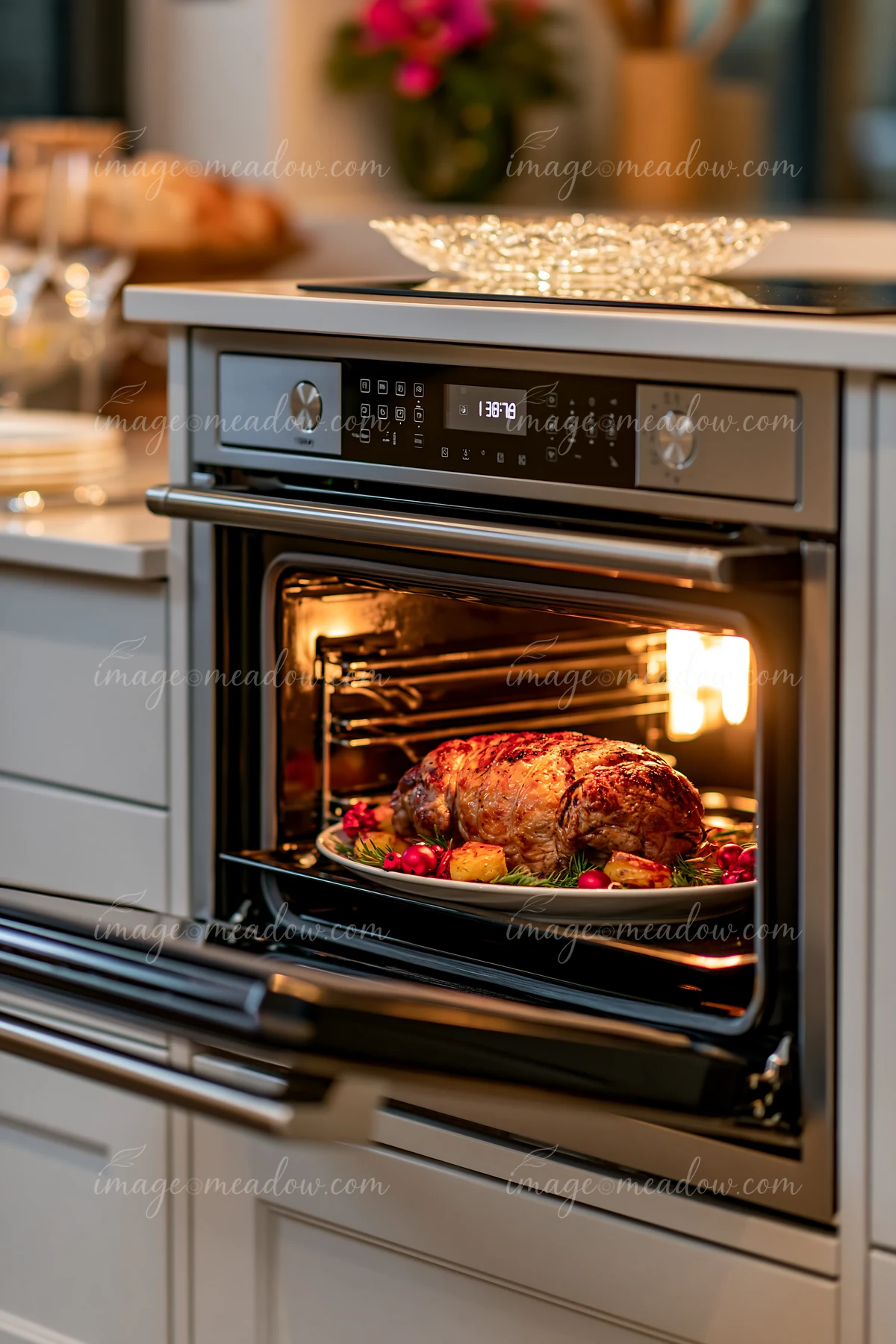 A roast sits on a platter in an open oven, surrounded by vegetables.