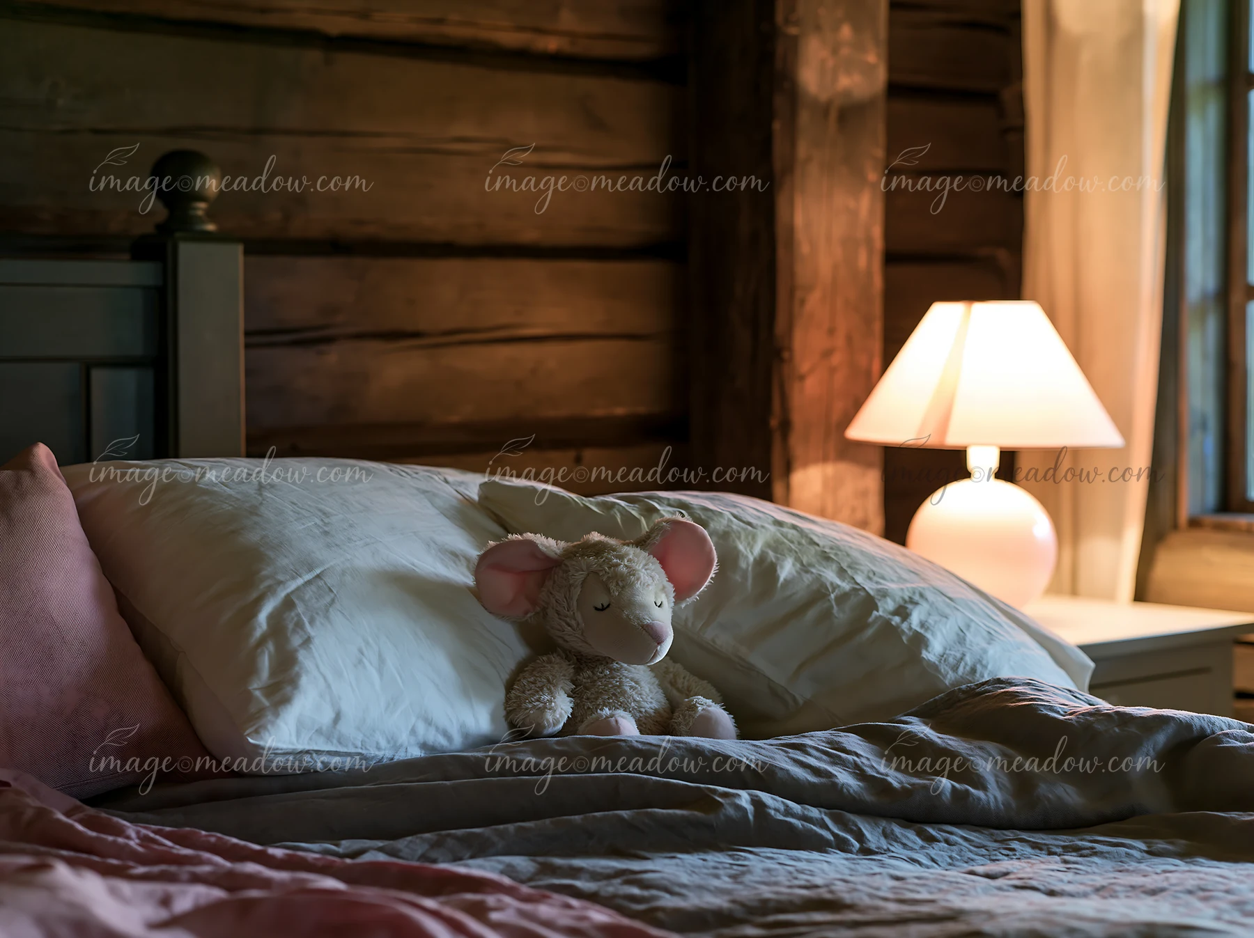 A rustic bedroom features linen bedding and a cute stuffed animal resting on a pillow.