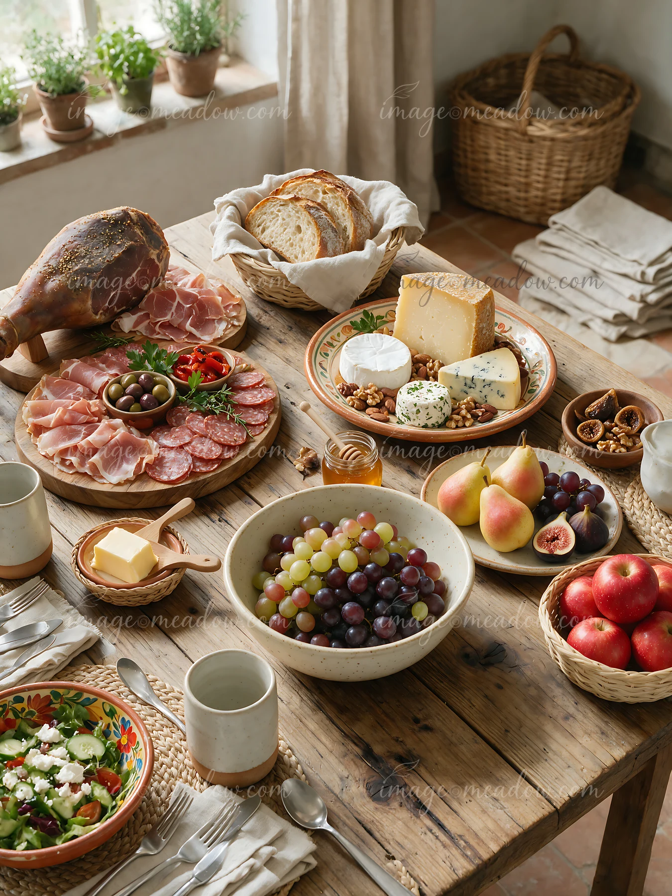 A rustic farmhouse buffet displays a variety of foods including cured meats, cheeses, fruits, and bread on a wooden table.