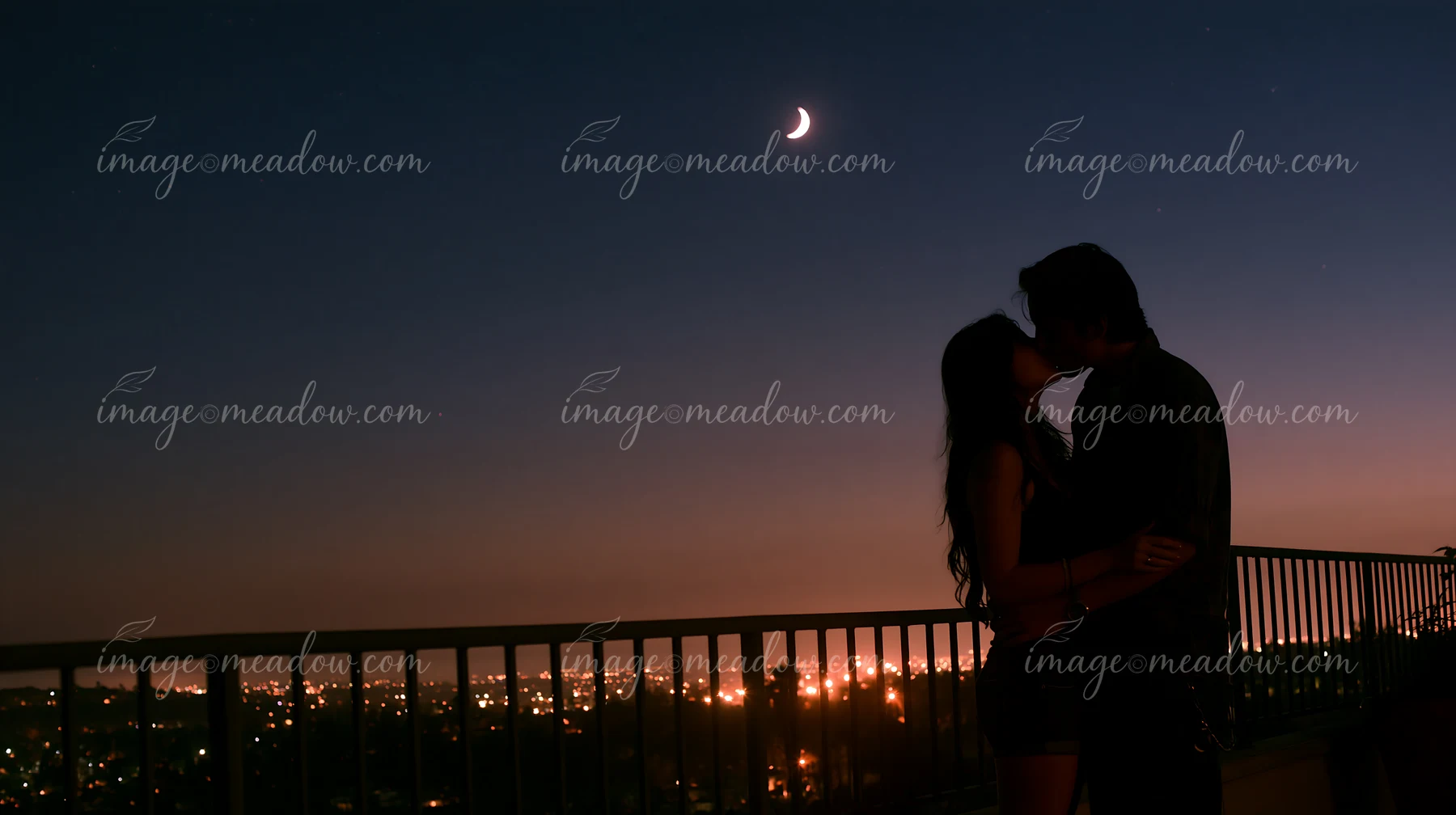 A silhouette of couple kissing under moon and stars captures a romantic moment at dusk.