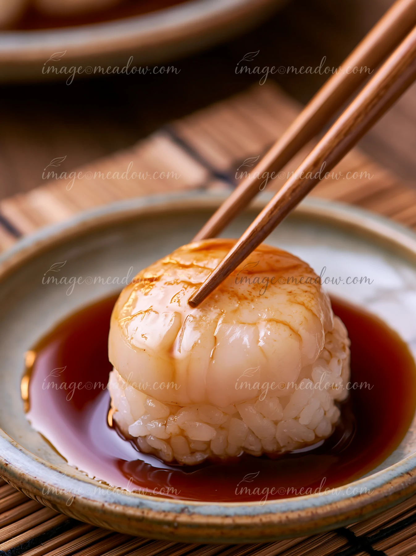 A single sushi piece rests on a shallow plate with soy sauce.