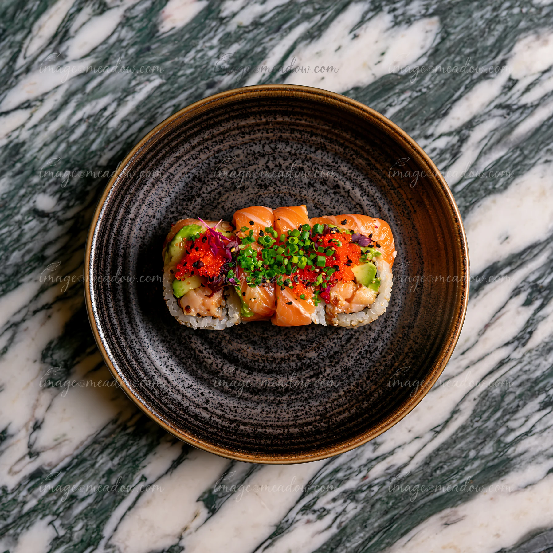 A single sushi roll on ceramic plate sits on a marble tabletop.