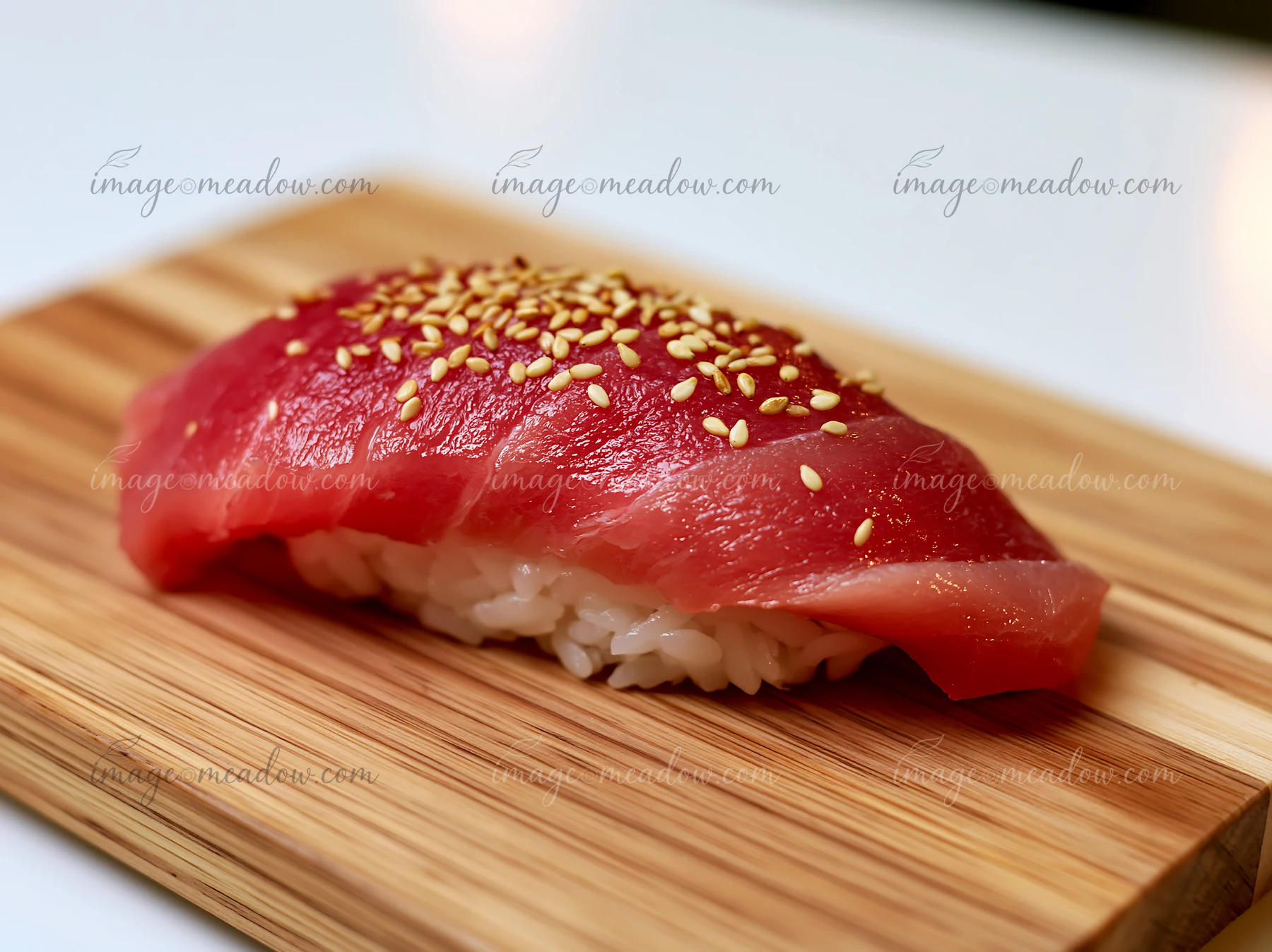 A single tuna nigiri on wooden board garnished with sesame seeds showcases fresh sushi.