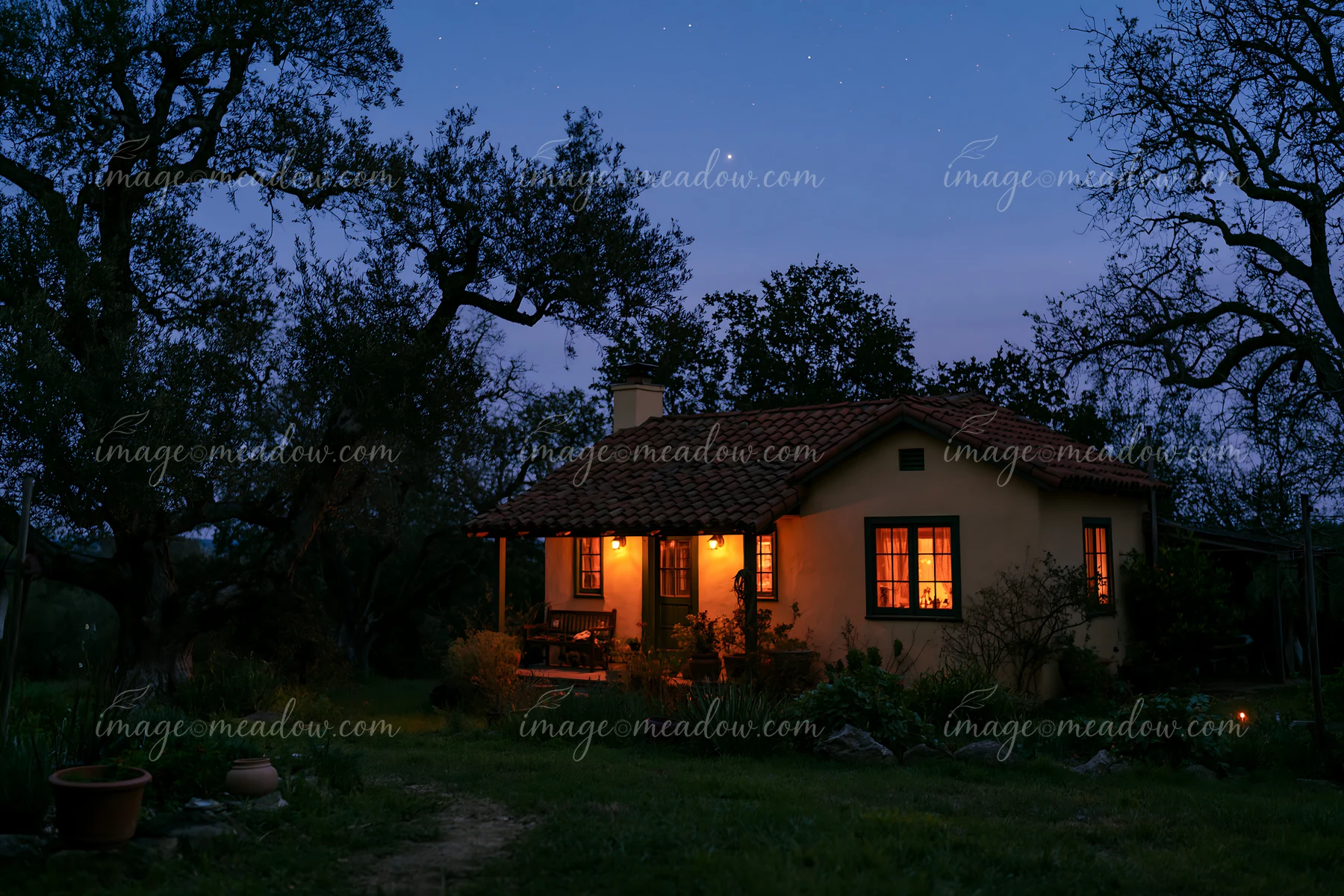 A small house stands under stars during blue hour, lit by warm lights.