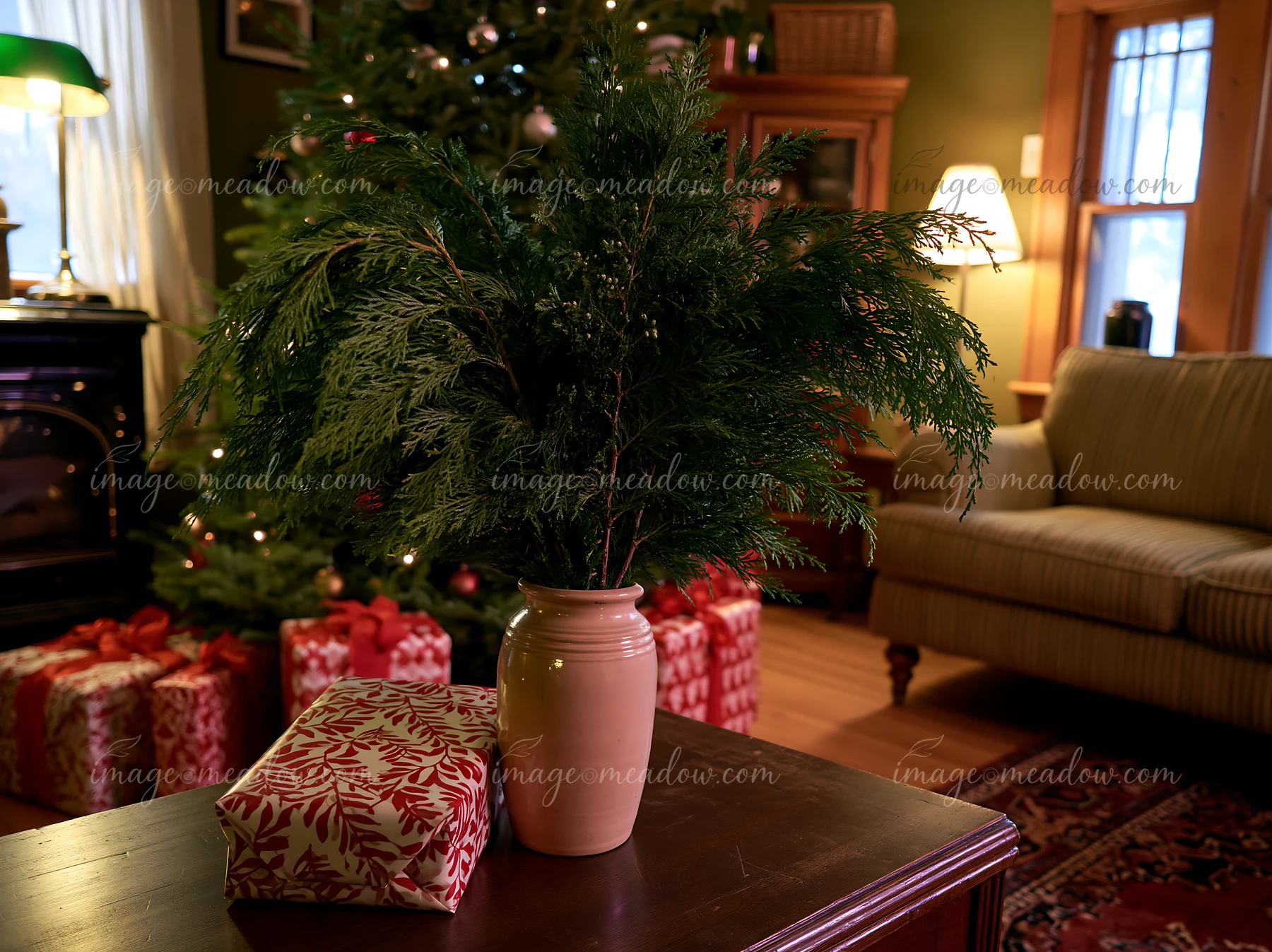 A small vase with greenery sits on a table in a cozy Christmas living room.