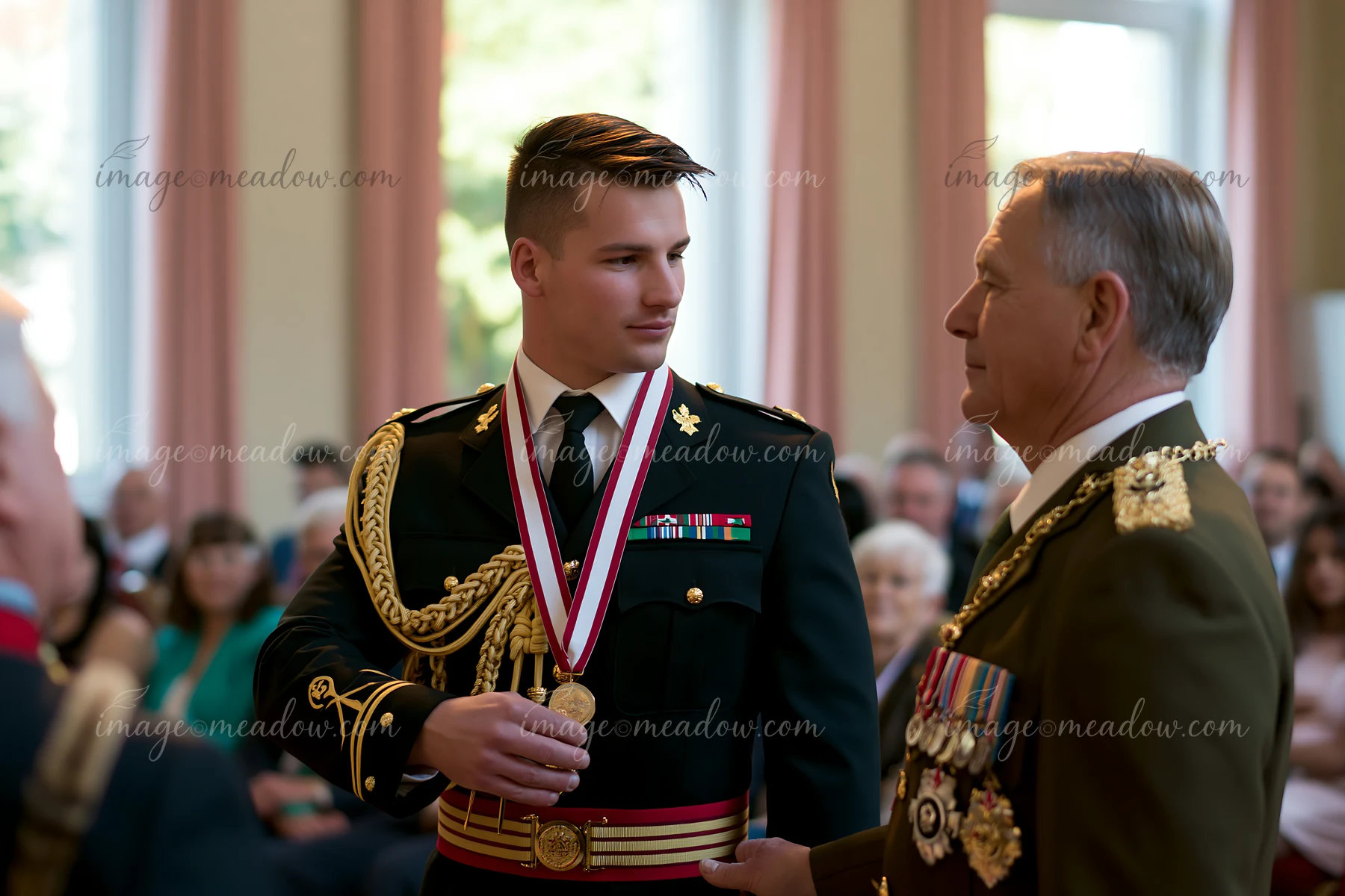 A soldier receiving medal stands in a formal setting, with an officer speaking to him.